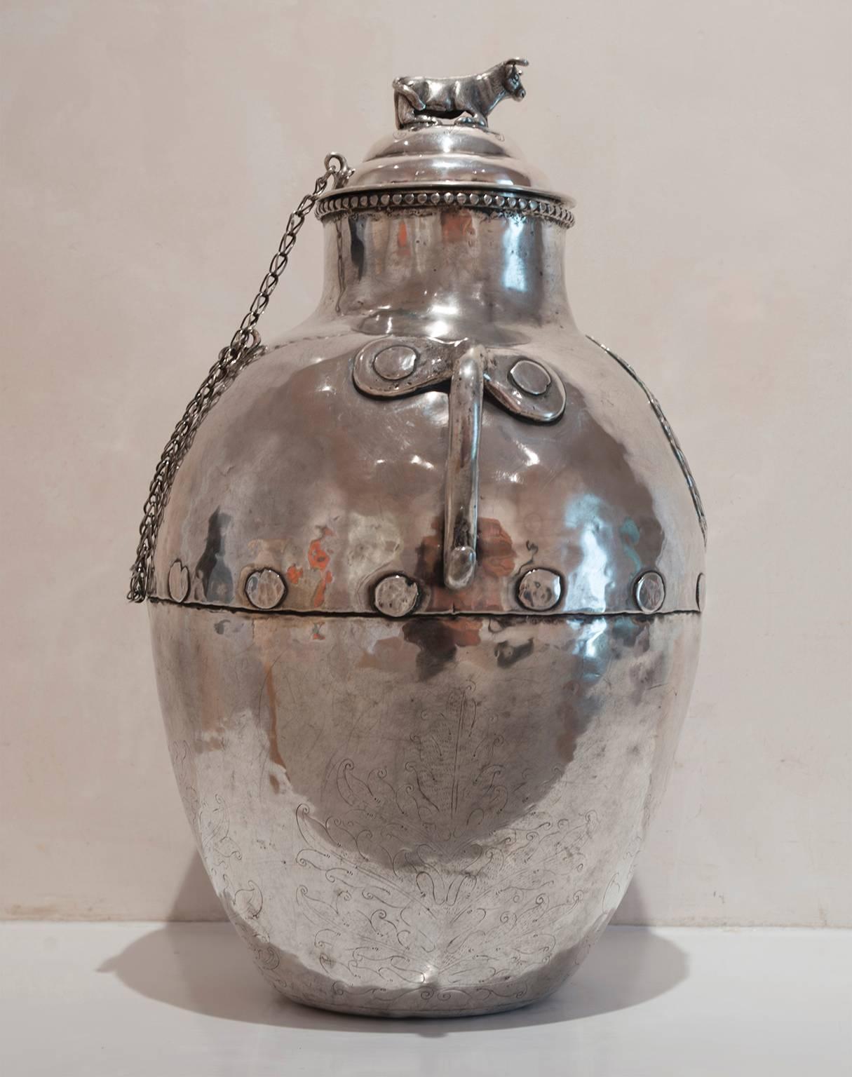 The domed cover with resting bull finial attaches to jug with chain, the jug with large raised coat of arms to front and engraved decoration to lower portion, applied handles. Approximately 188 troy oz.