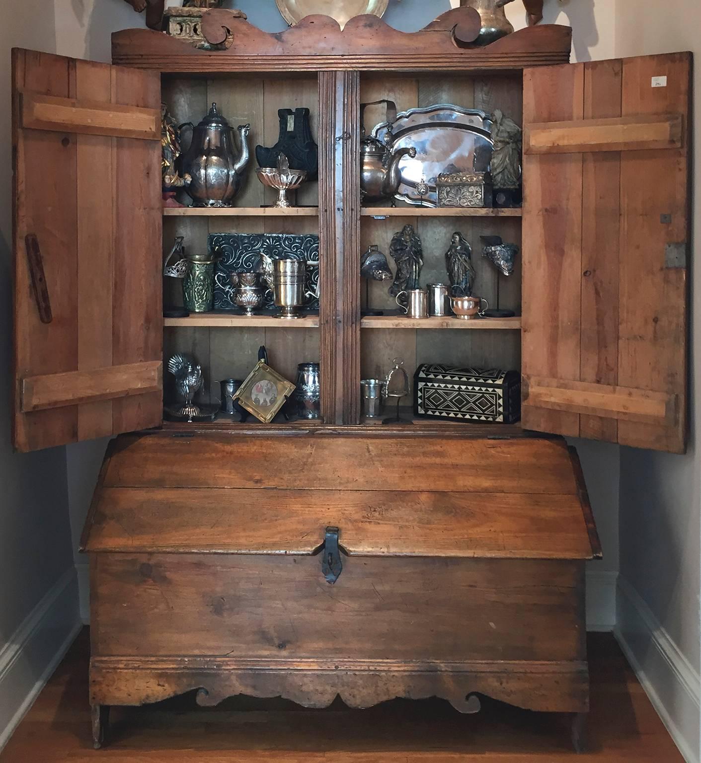New Mexican pine cabinet set on top of a grain storage bin. 

The scrolling rectangular pediment above two reeded cupboard doors opening to two shelves, above a canted hinged lid opening to a well, with scrolling apron, the sides continue to form