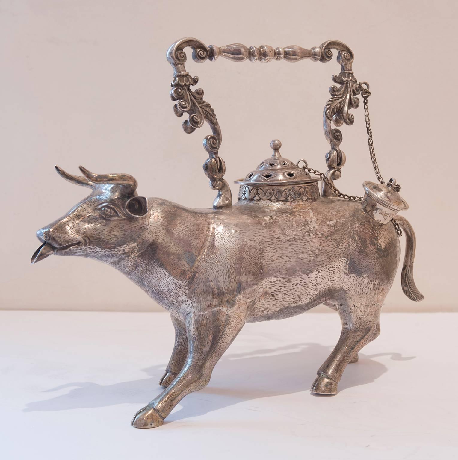 Large continental cow form aquamanile or warming teapot. Crafted out of sterling silver. Features a well-sculpted hollow body with rare warming area. Round drawer slides out of the side for hot coal placement. Caps attached to chain to fancy handle.