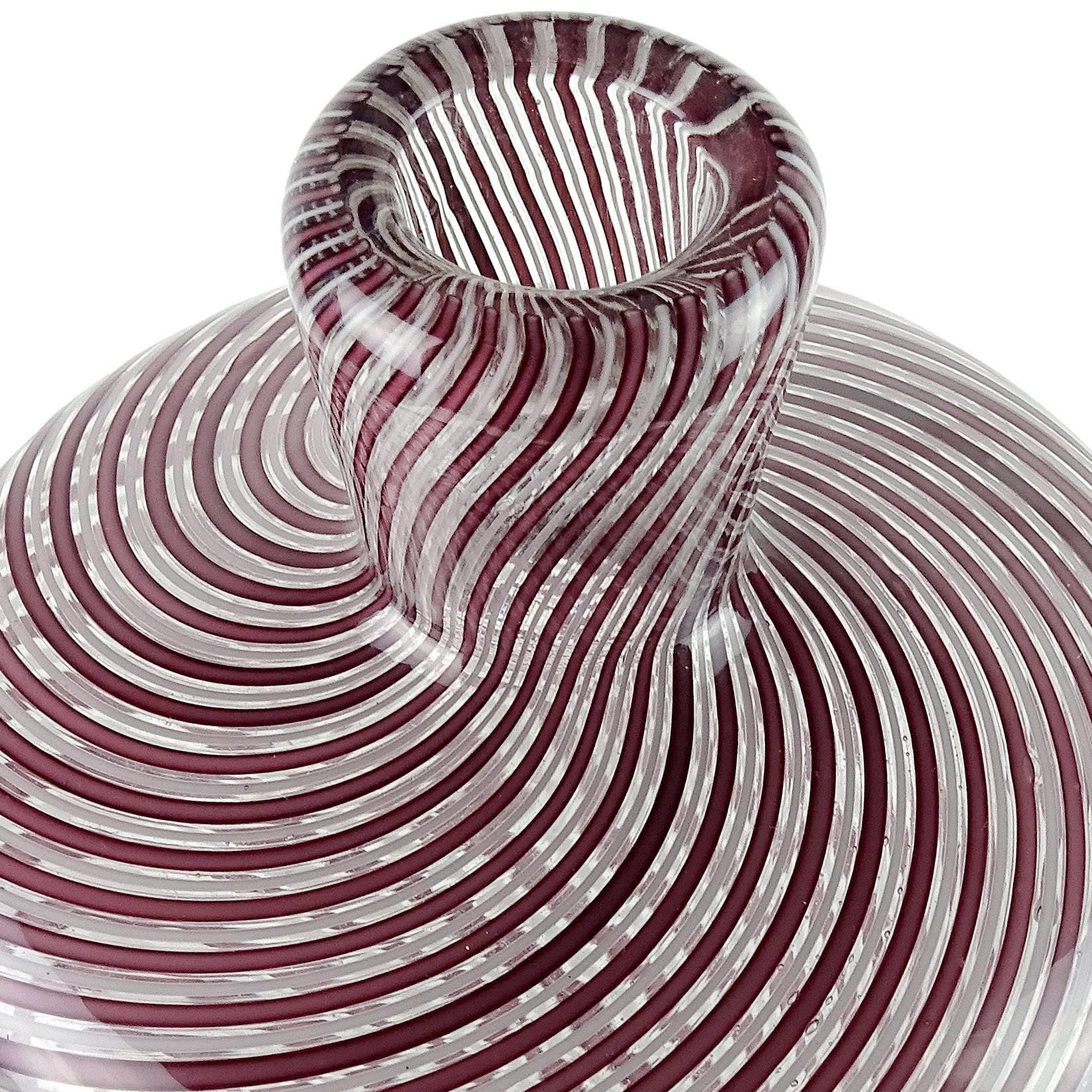 Beautiful Murano hand blown purple and white ribbons art glass corset flower vase. Attributed to designer Dino Martens for Aureliano Toso. The piece has an optic swirl design, with cinched in body. Measures 10 3/4" tall x 4 1/2" wide. 
