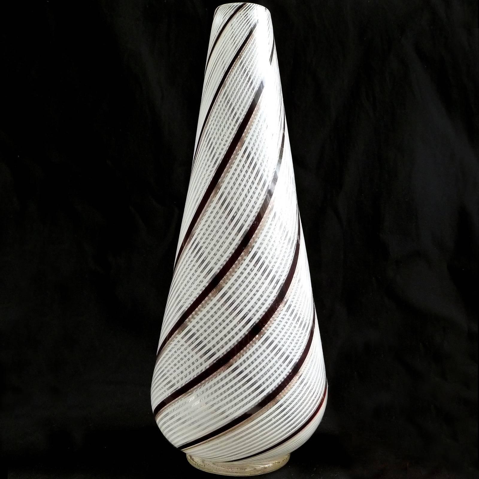 Beautiful Murano handblown filigrana white, black and aventurine flecks ribbons Italian art glass flower vase. Documented to designer Dino Martens, for Aureliano Toso. It still retains its original label underneath. It rests on a glass disk with