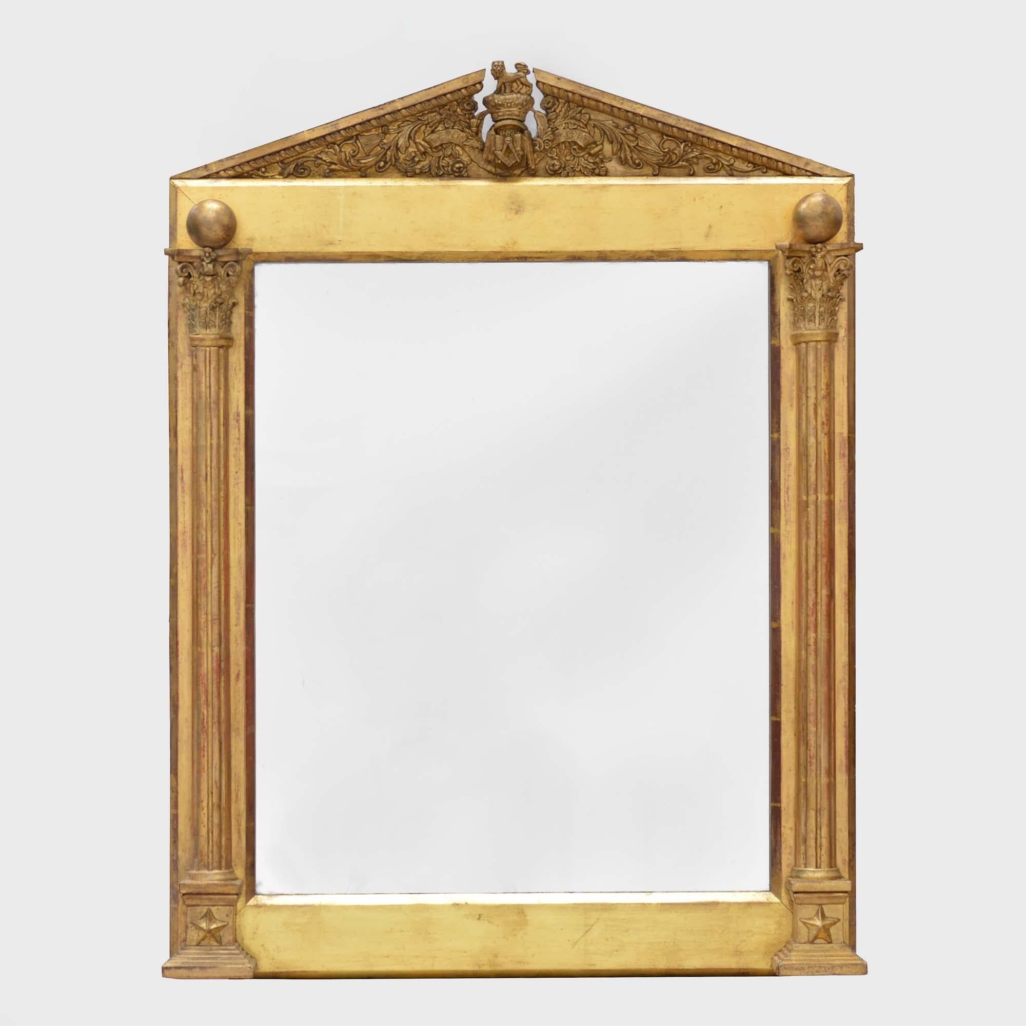 19th century giltwood mirror
With broken arched pediment adorned with acanthus leaves, centred with the crest of the square and compass of the Freemasons, flanked with fluted columns with Corinthian capitals. The original water gilding with some