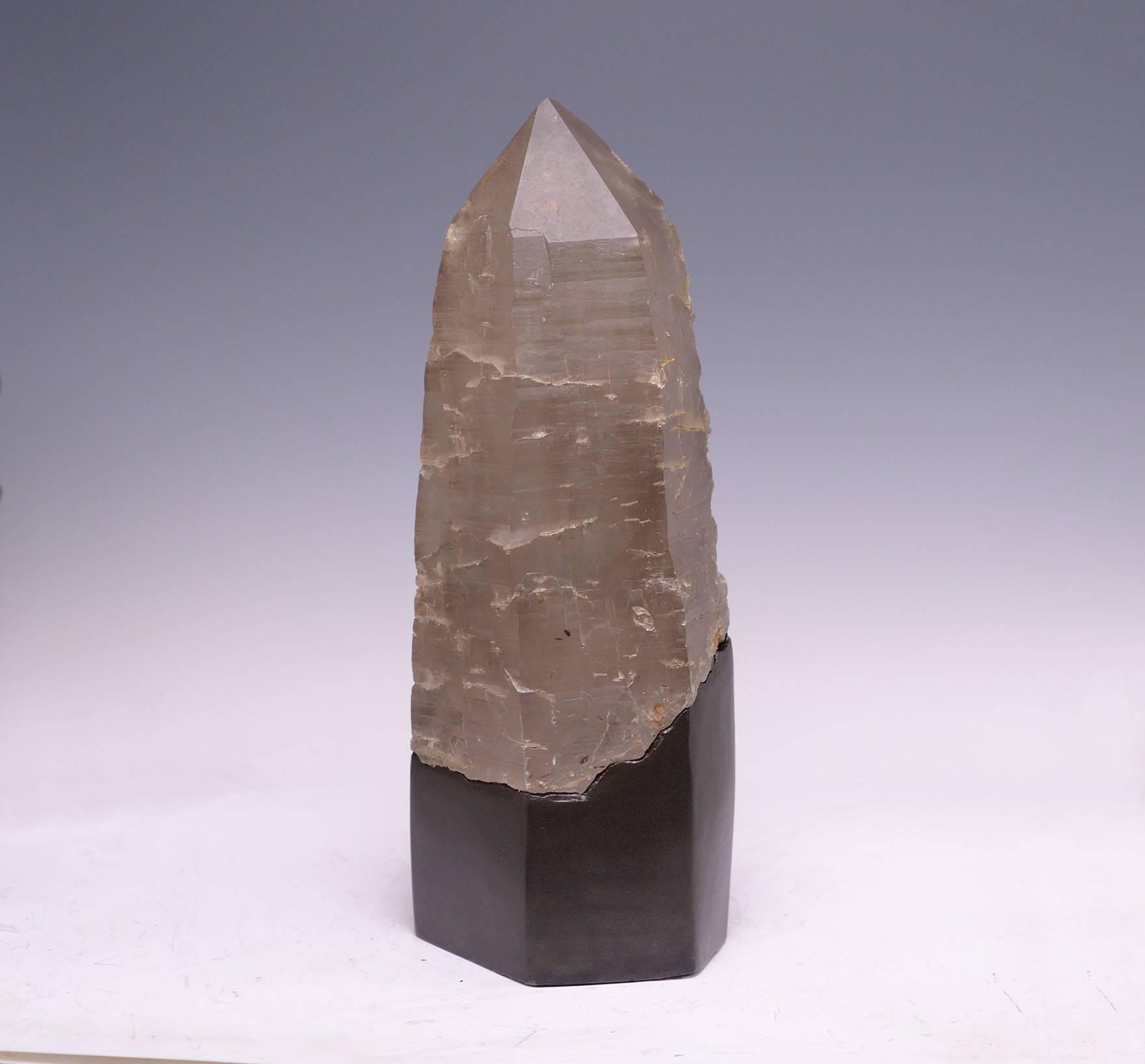 A beautiful grey rock crystal quartz obelisk with painted wooden base.
