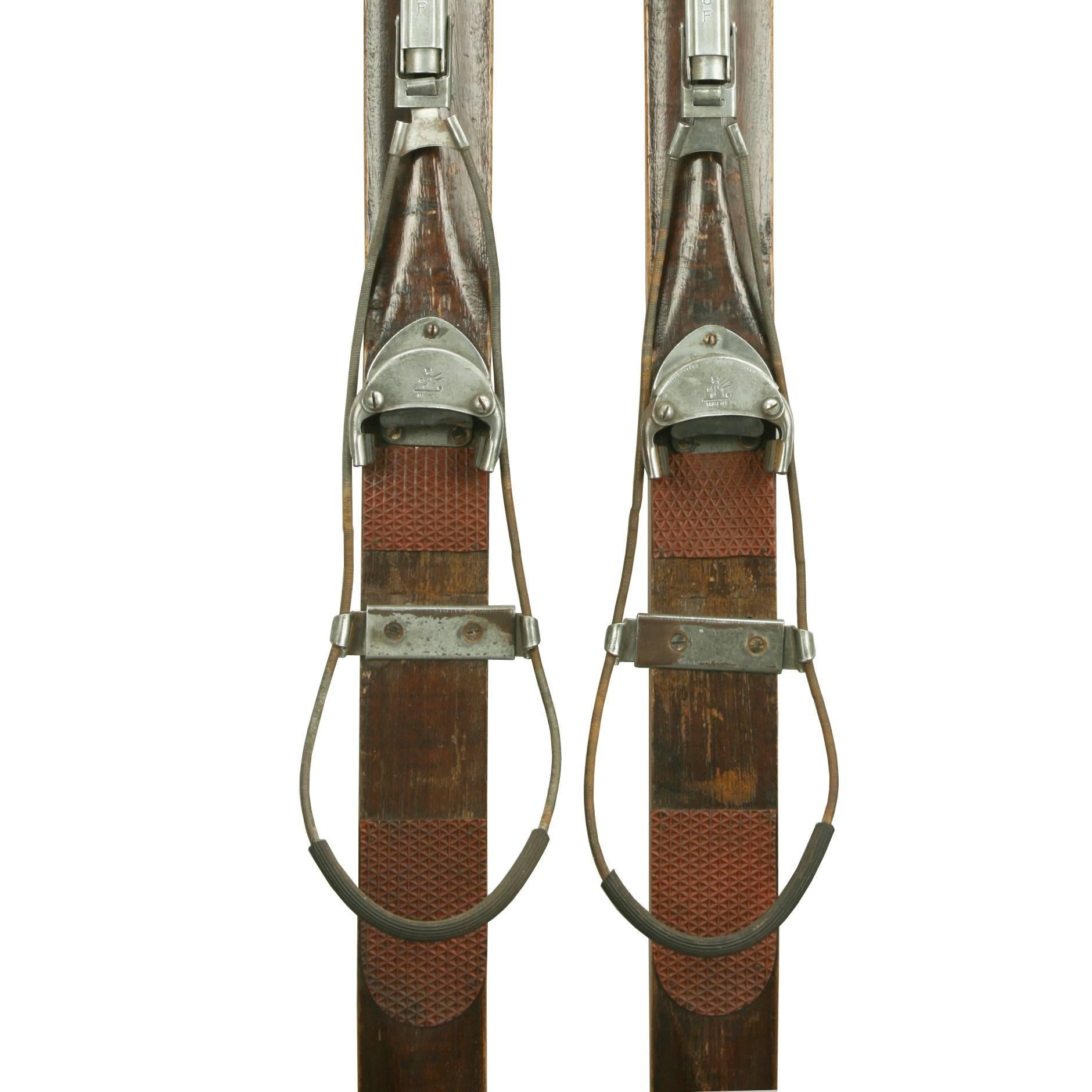 A nice pair of ridge top ash skis with rubber foot plates and galvanized safety bindings. The bindings have a Trusetal toe unit that was designed to allow the toe of the boot to pop out during a fall. The binding plate is marked 'TRUSETAL' with a