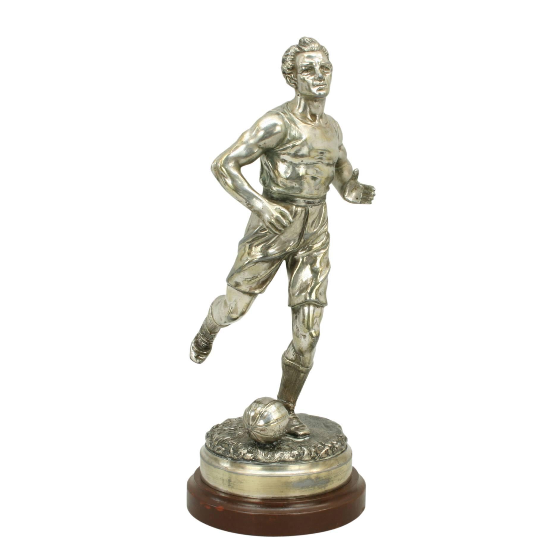 A very nice French spelter figure of a footballer. The footballer is about to kick a football with his right foot, the football is an early shaped ball. The figure is mounted onto a turned wooden base. The sculpture is signed "Gregoire" on