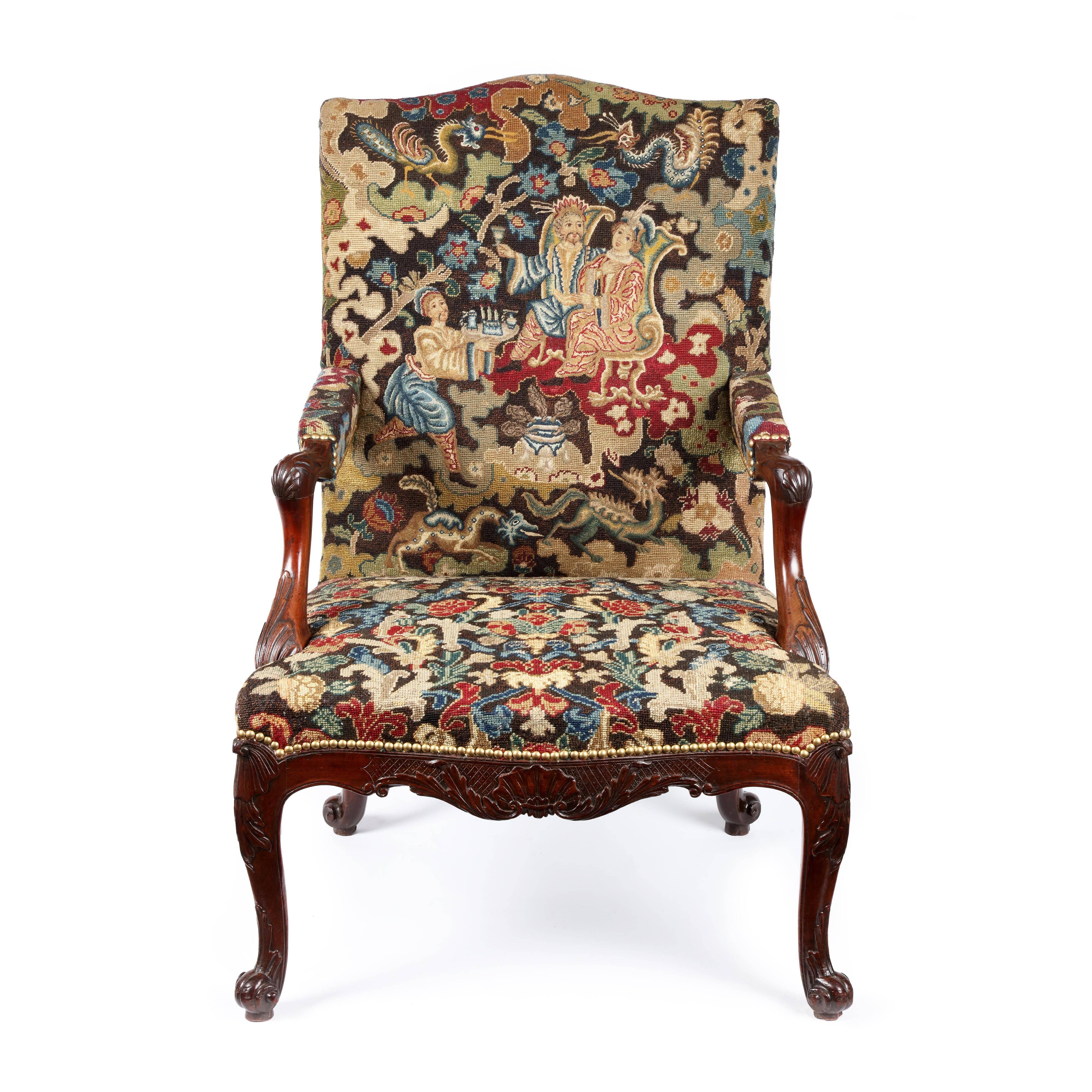 A fine George II carved mahogany Gainsborough chair upholstered in a period 18th century needlework. The upholstered needlework back of serpentine form, the arms with carved shell scroll terminals above in-curved moulded supports edged with rope