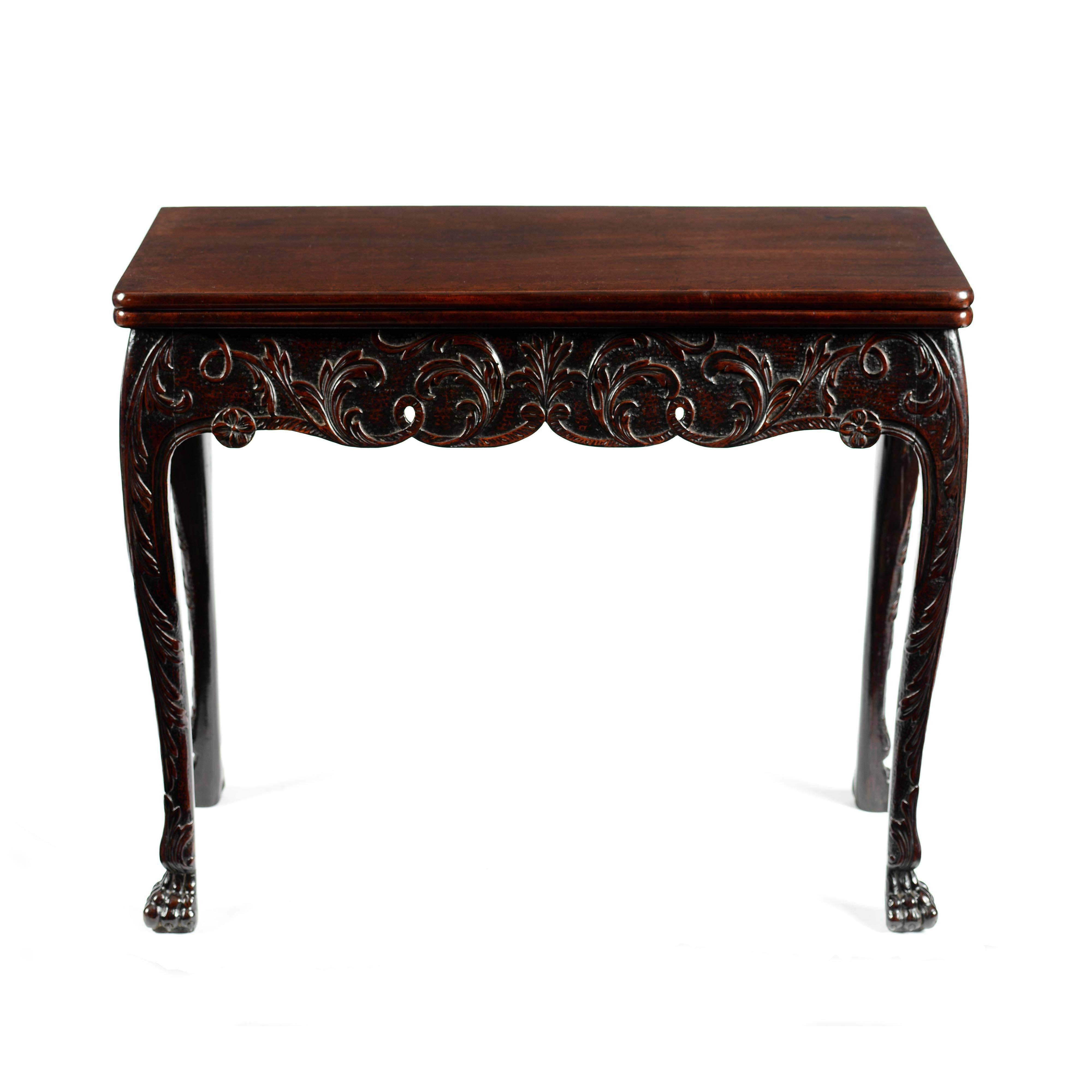 A superb very rare Irish George II Cuban mahogany card table, retaining excellent original color and patina. The rectangular top with moulded edge, over a delightful, crisp leaf and flower profusely carved scroll shaped frieze, integrating elegantly