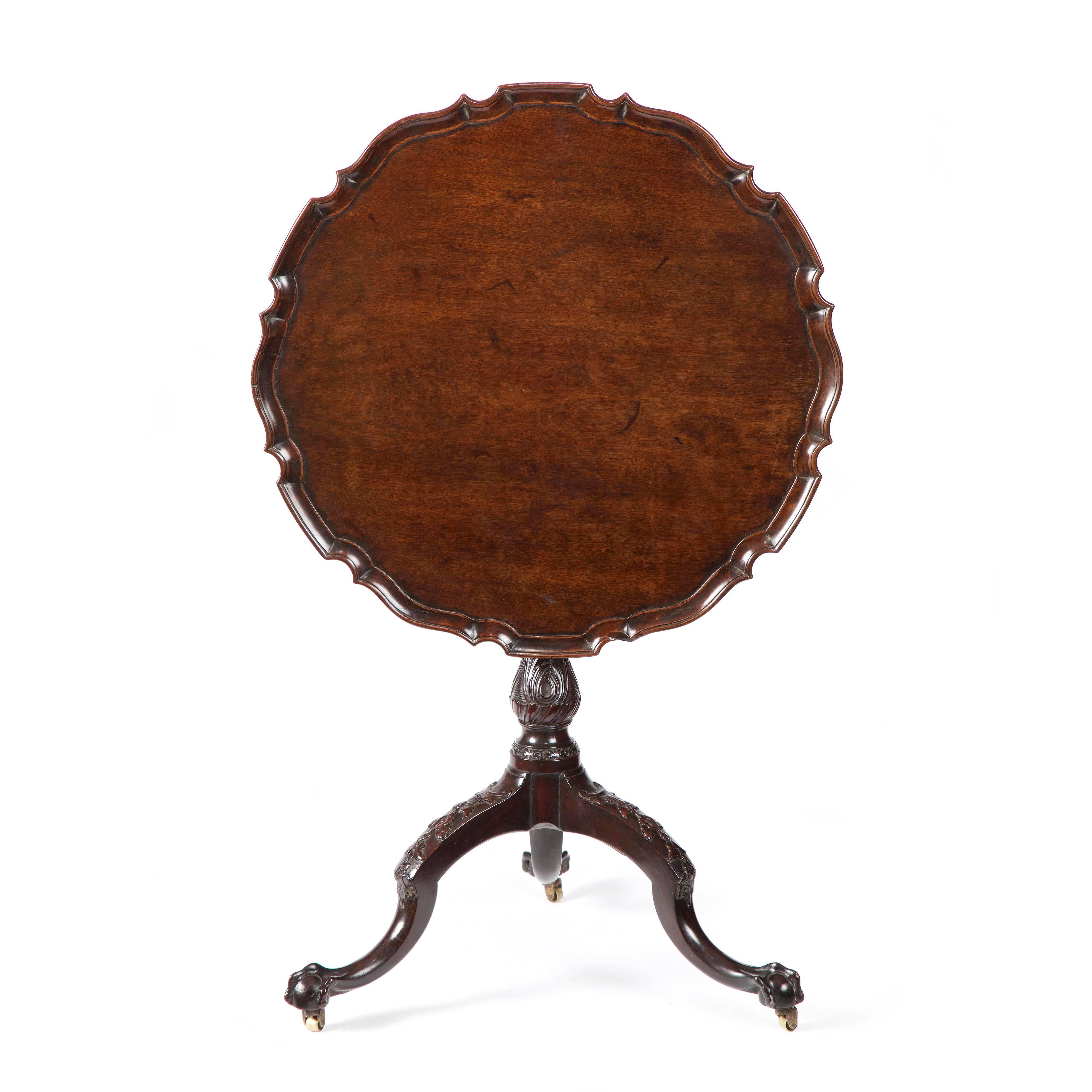 A fine George III carved mahogany piecrust tripod table retaining excellent original color and patina. The well figured top with a crisply carved and moulded “piecrust” edge, with a “snap top” tilting action. The top is supported by a tapering