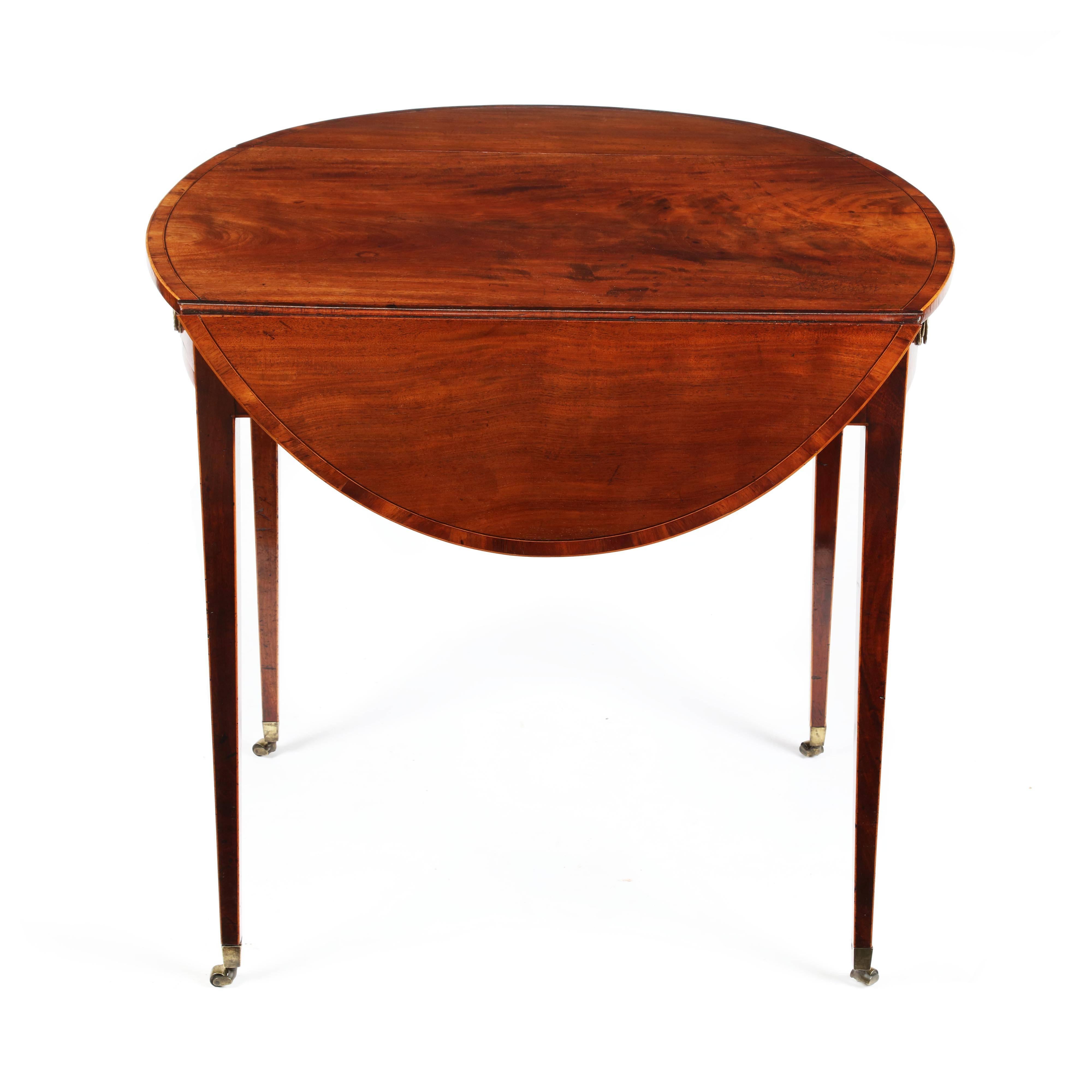A fine George III mahogany and rosewood crossbanded oval pembroke table. The top of oval form with a well figured mahogany top, cross-banded around the circumference with rosewood, strung with box and ebony. The frieze with bow fronted back and