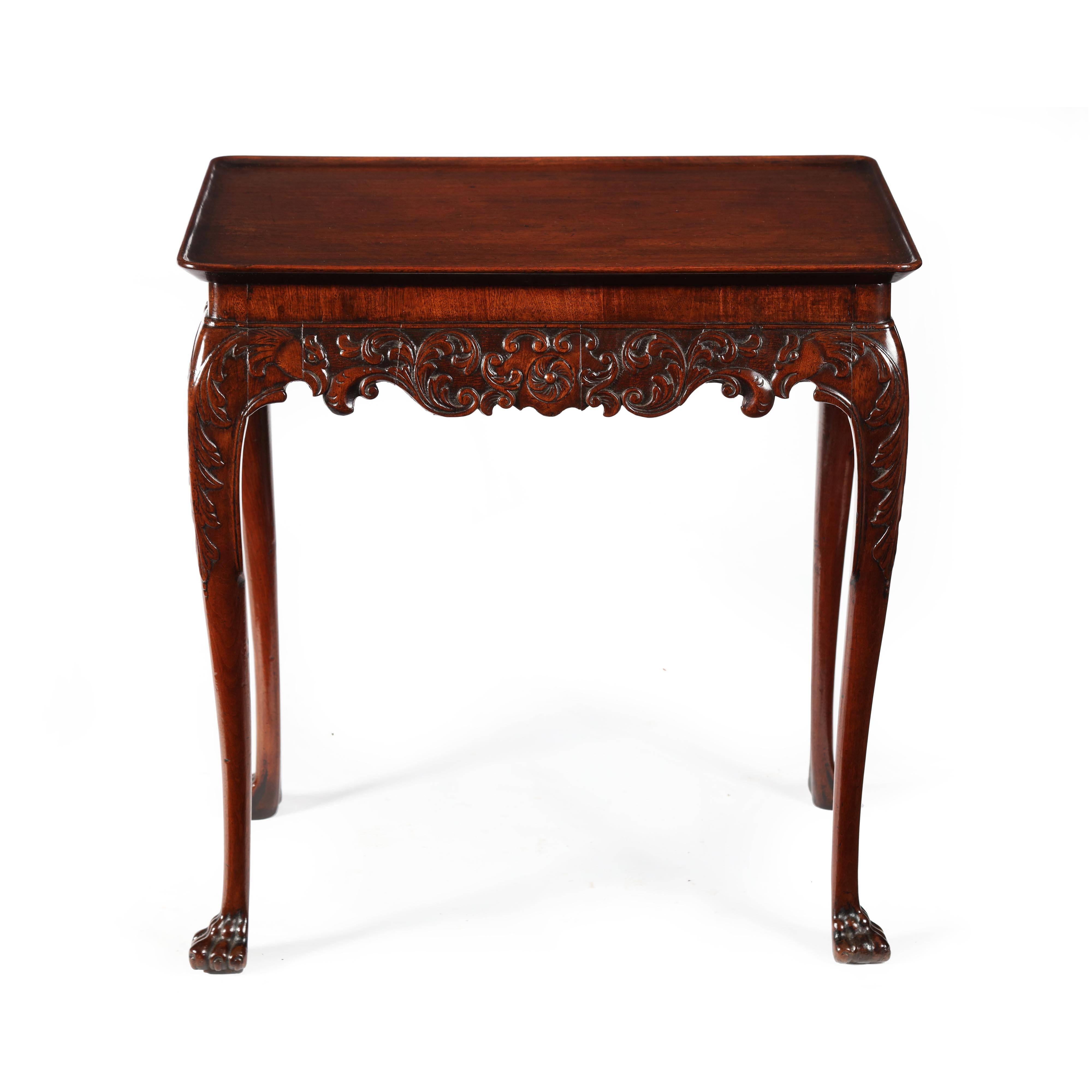 A superb George II Cuban mahogany carved Irish silver table of compact proportions. The solid mahogany, rectangular top with carved dished lip around the perimeter. The scrolling profusely carved with a central flower bordered by trailing carved