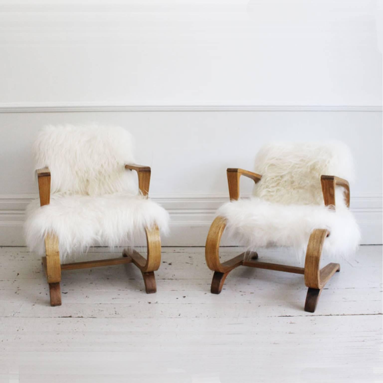 A pair of very stylish and incredibly unusual ash cantilever chairs in the style of Audoux-Minet. We have had them recovered with Icelandic Sheepskin and absolutely love the results. These chairs are very chic and would look fabulous pretty much