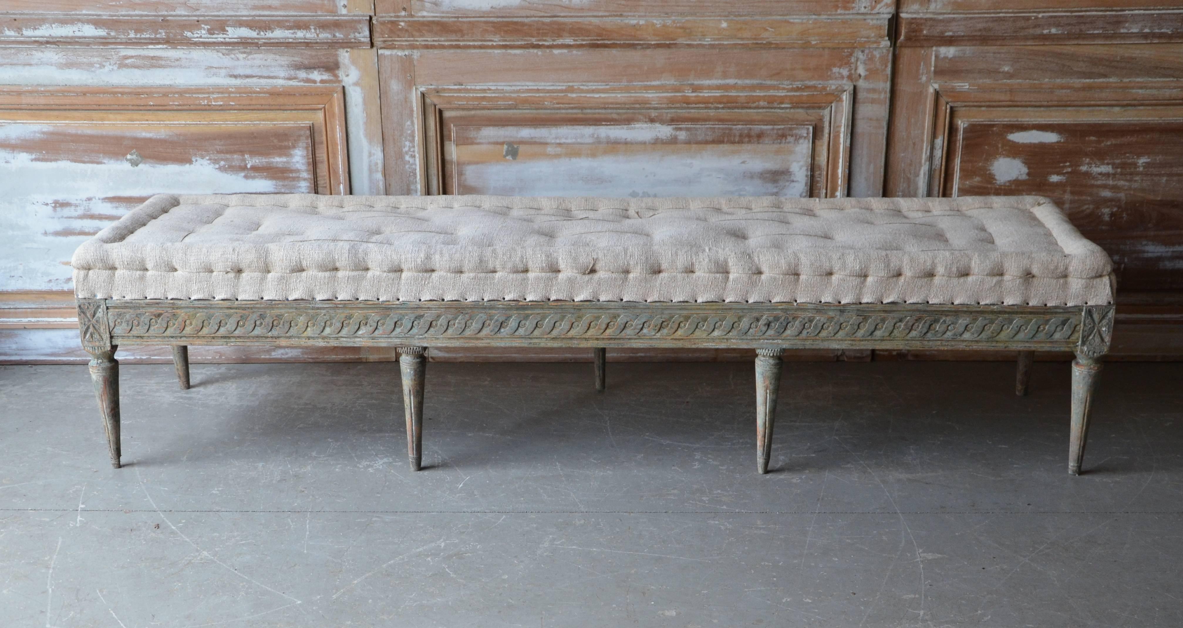 Swedish period Gustavian long bench, circa 1790, finished on three sides with richly decorated carvings on carved round fluted legs. Original blue/green time worn patina and upholstered in traditional way in antique hand-stitched linen. Timeless