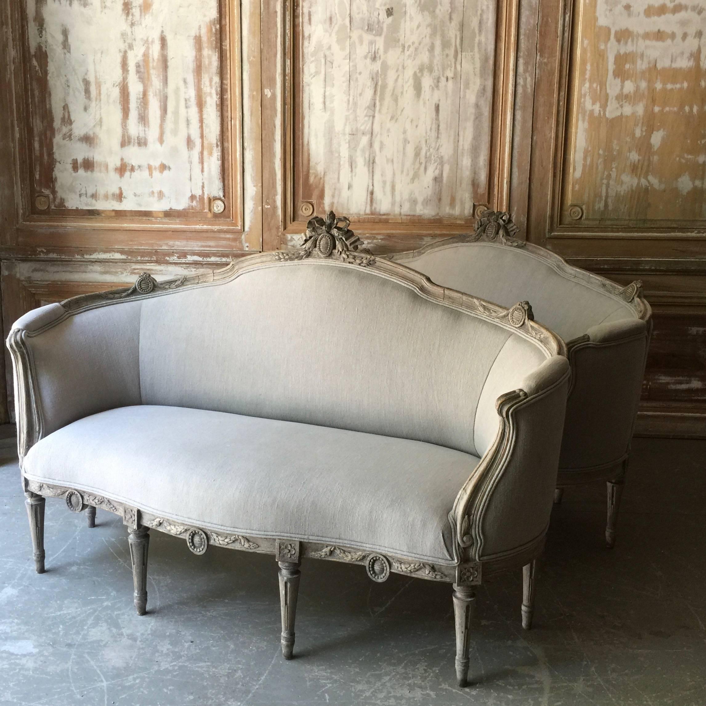 Very rare pair of decoratively carved Swedish Gustavian style sofas with back carved in knot of ribbon, fluted arms, carved apron and corner blocks on turned tapering legs.
The comfortable curved ends make these an excellent conversation