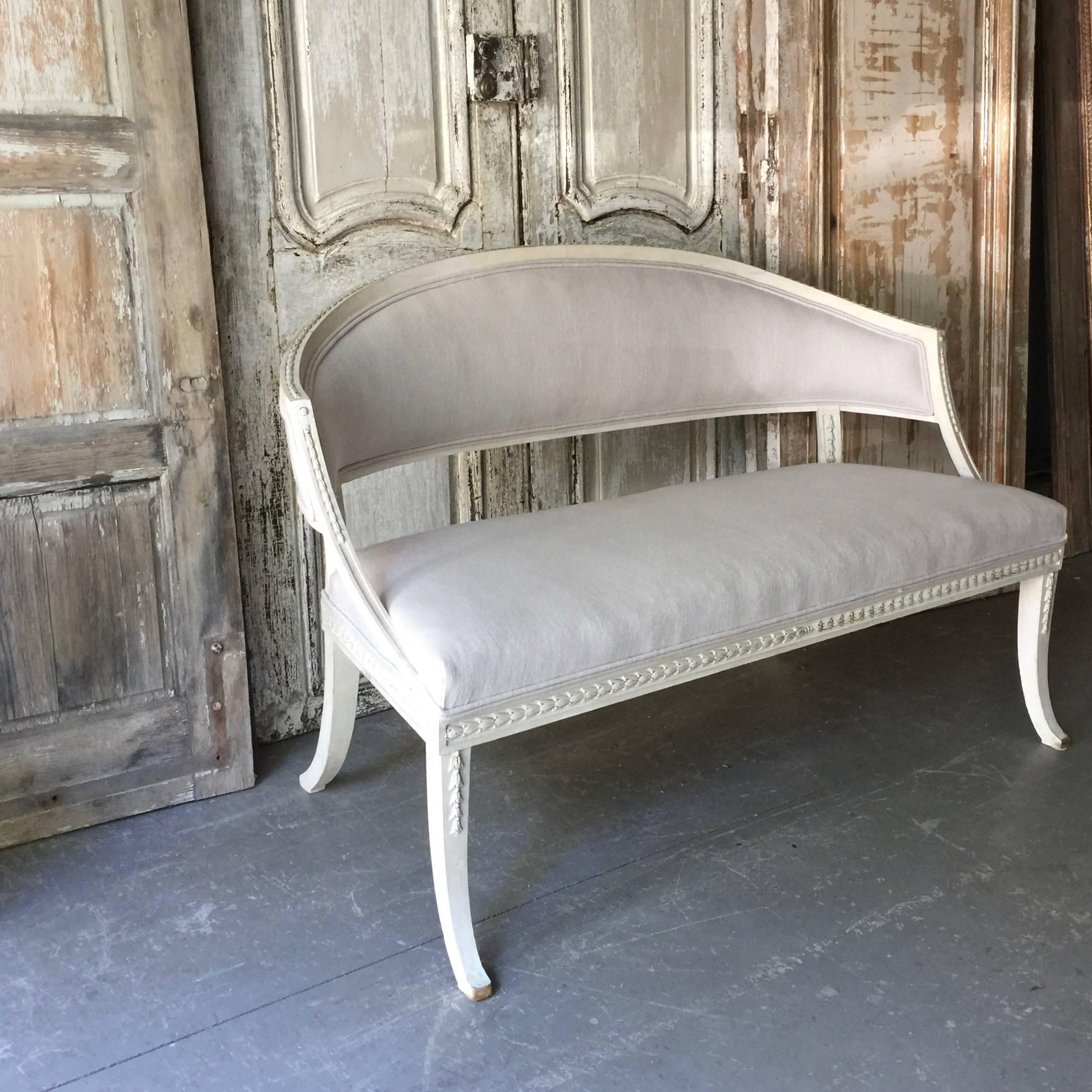 Charming small Swedish 19th century barrel back sofa settee with rounded form, elegant long saber legs and rails carved in horizontal beading, rosettes and ribbons. Scraped to original paint and upholstered in new linen, 
 Sweden, circa 1860.
Here