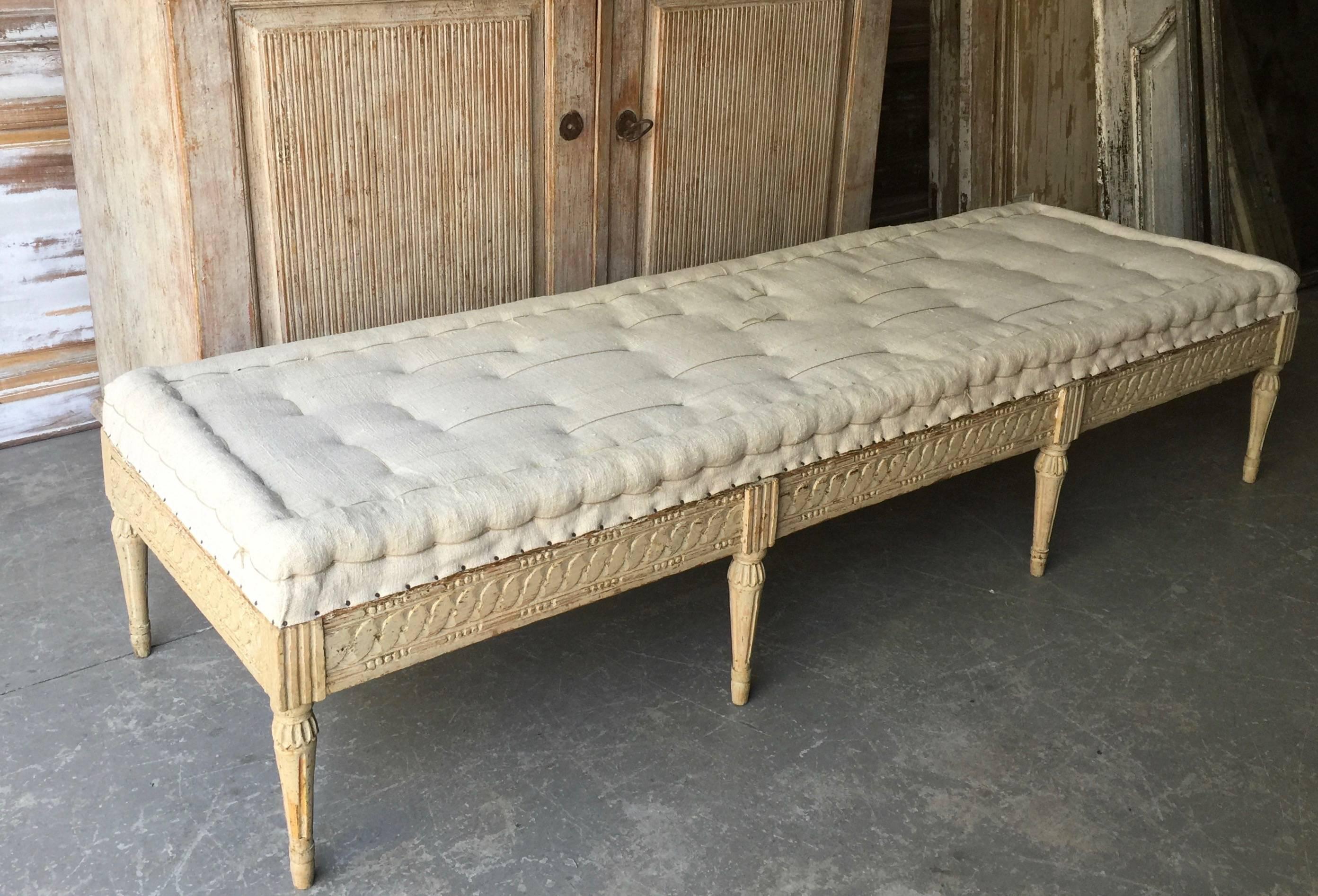 Swedish Gustavian period bench, circa 1800, finished on three sides with Guilloché carvings on carved round fluted legs. Scraped to original cream /white finish and upholstered in traditional way in antique hand-stitched linen. Timeless antique