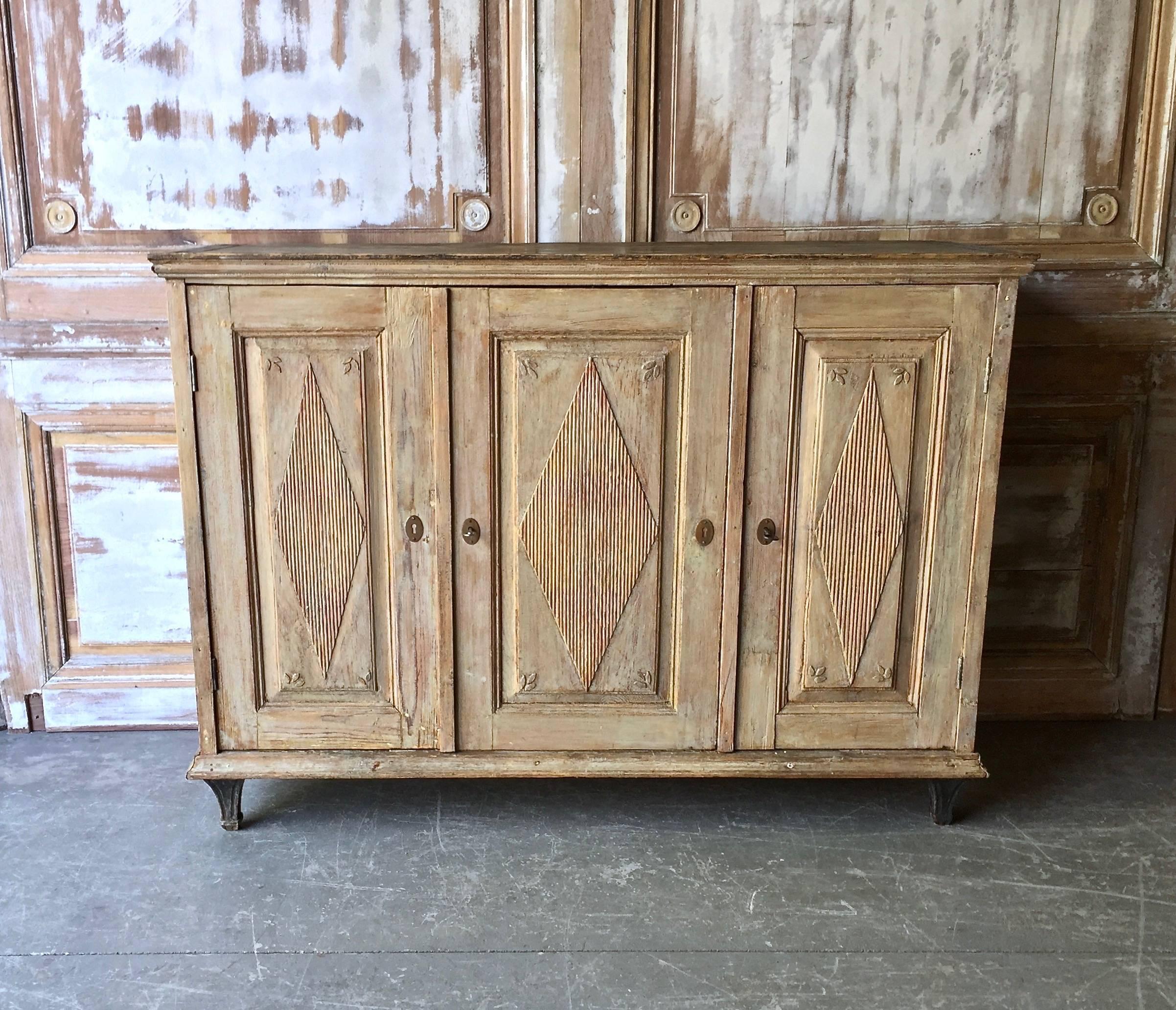 Early 19th century Swedish Gustavian sideboard in Classic Gustavian style with reeded three panelled doors with diamond shaped lozenges and charming carved flower petal decors, on tapered feet. Scraped to its original color with hint of palest blue