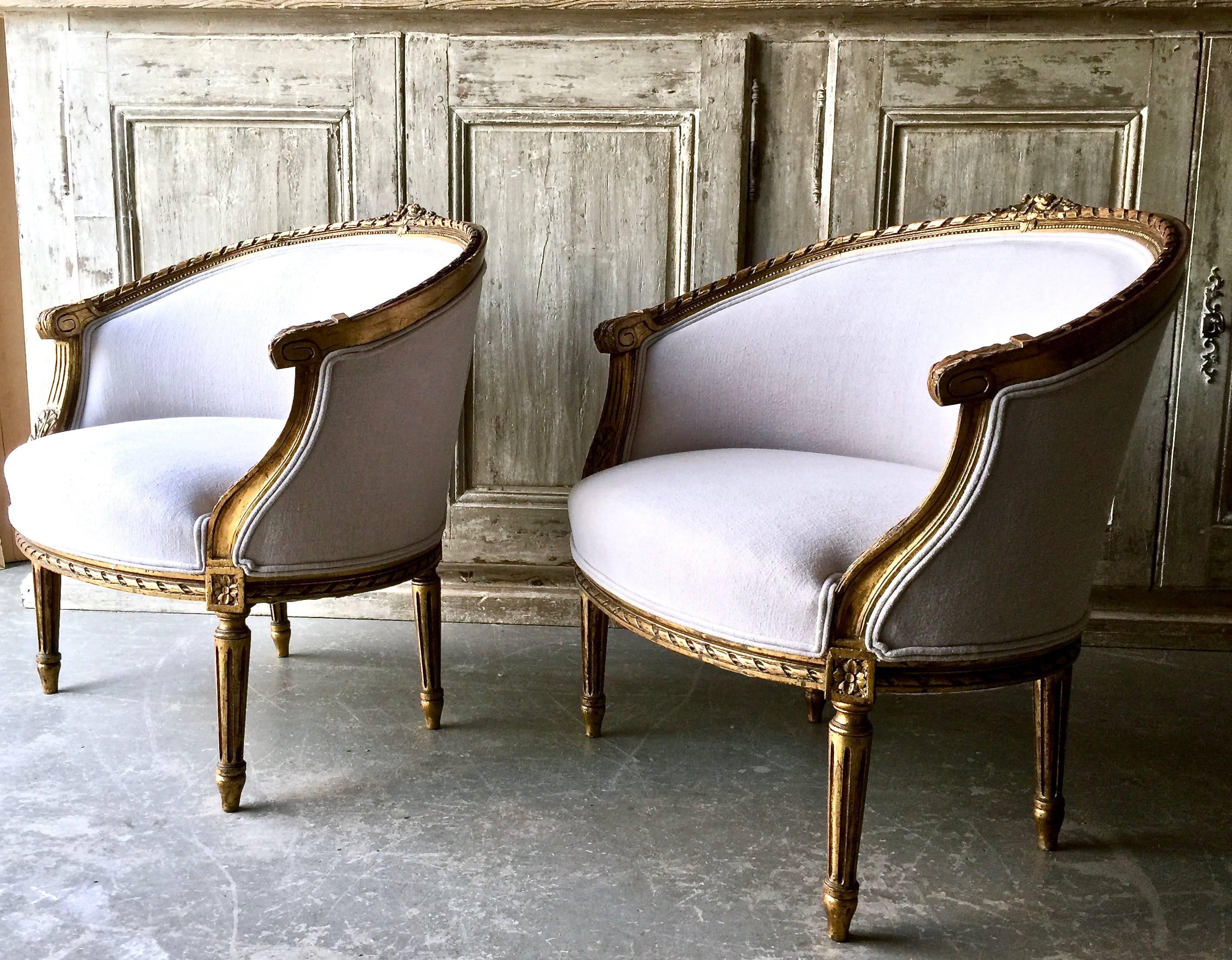 A fine pair of 19th century French Gondola bergères in Louis XVI style. The giltwood frames richly carved; the top gracefully curved, the seat rails and the fluted legs with florets. Completely re-upholstered in pales of palest grey linen,
France,