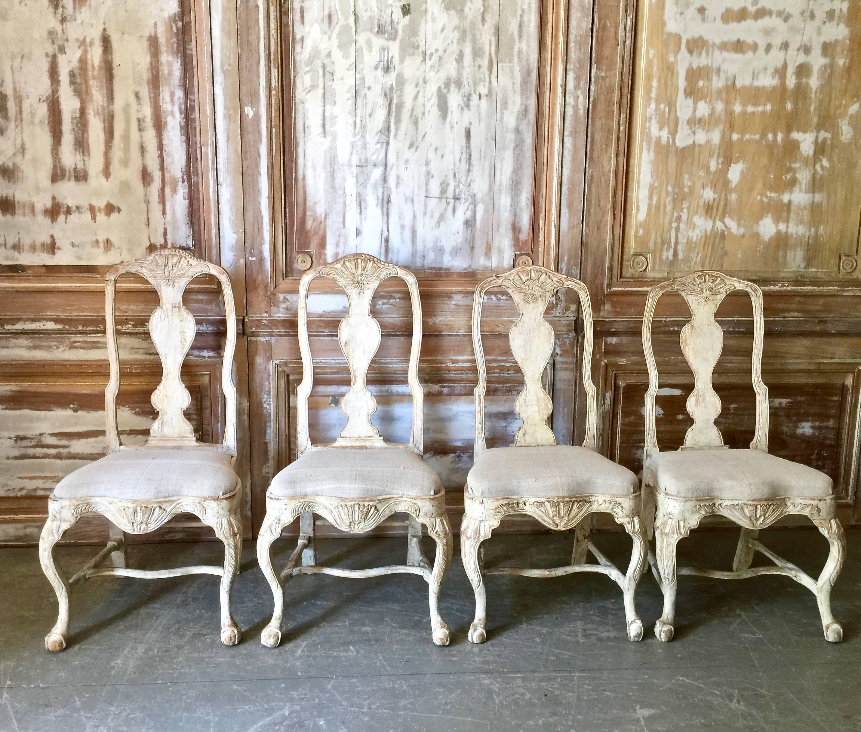 Charming Family of four 18th century Swedish chairs in Rococo period, circa 1760. Lovingly handmade with richly carving in traces of their original worn patina. Each chair being made in slightly diffrent hight. Upholstered with antique raw linen.