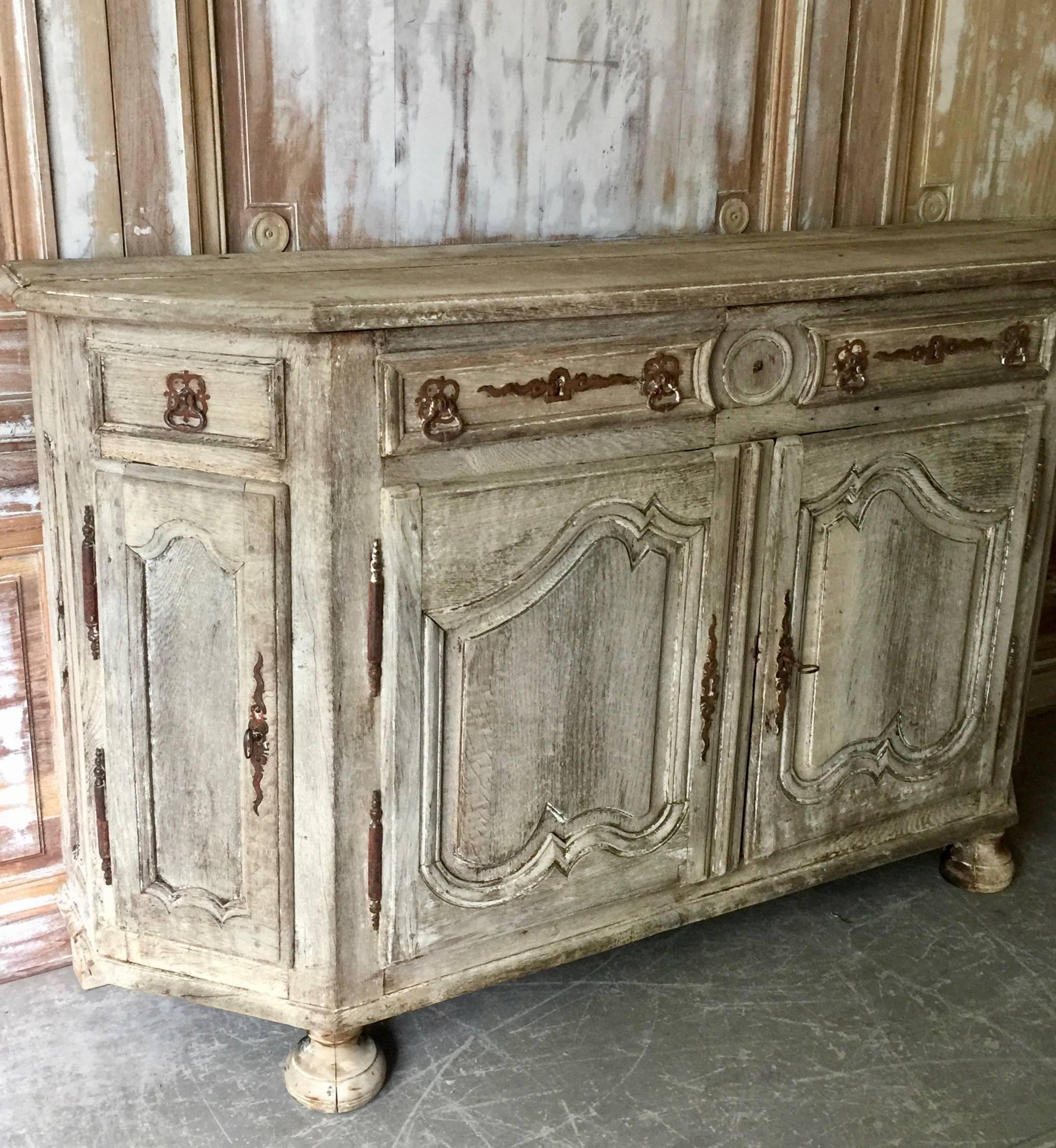 Handsome 18th century French enfilade or sideboard, in Louis XV manner with shaped top and richly carved fielded door panels on front bun feet in superb patinated natural oak. Original rustic ironwork.
France, late 18th century.
More than ever, we