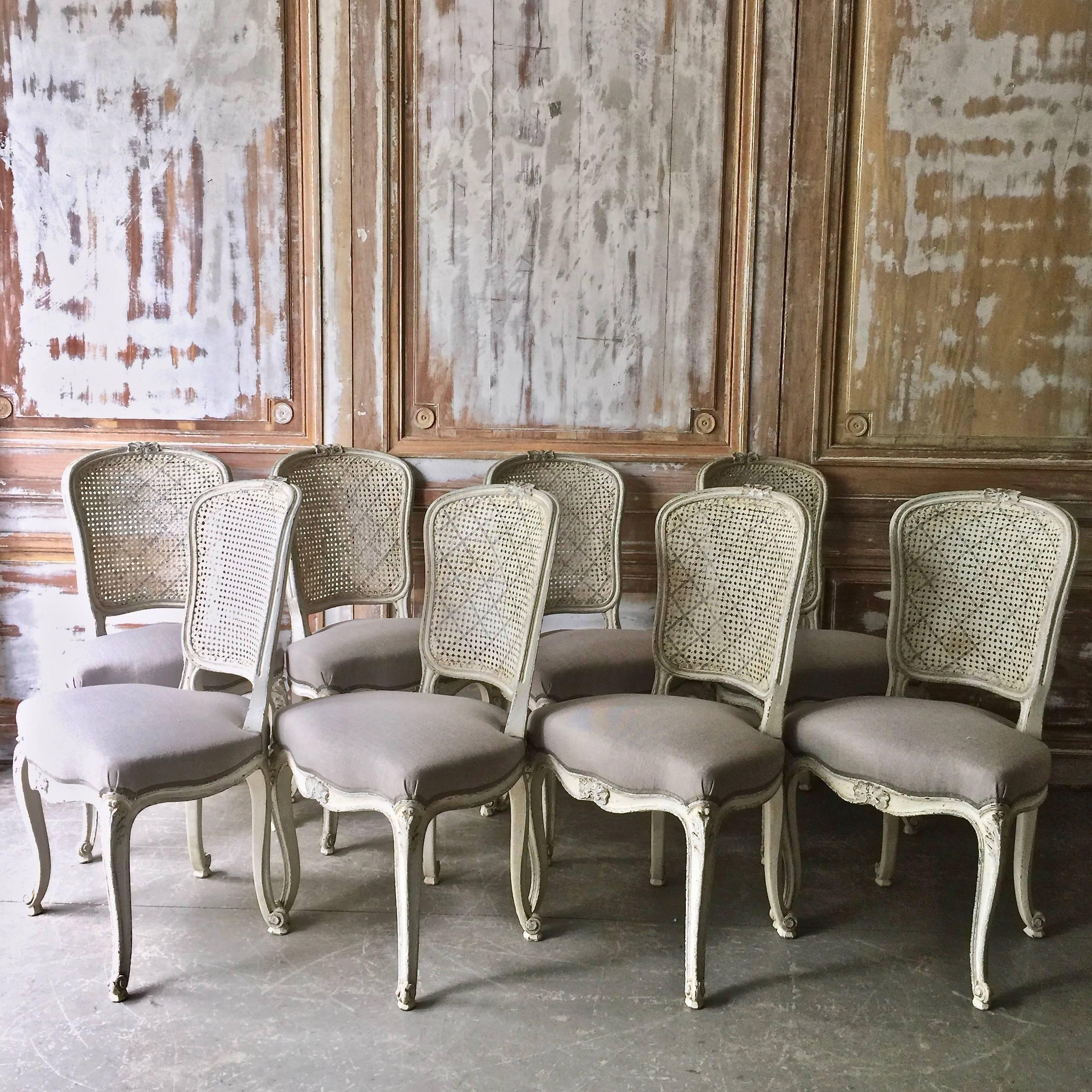 Set of eight French dining chairs Louis XV style with flat back called “la Reine” is caned and scalloped frieze carved and raised on cabriole legs. Upholstered in light gray linen with classical decorative gimp trim. Very elegant as well as