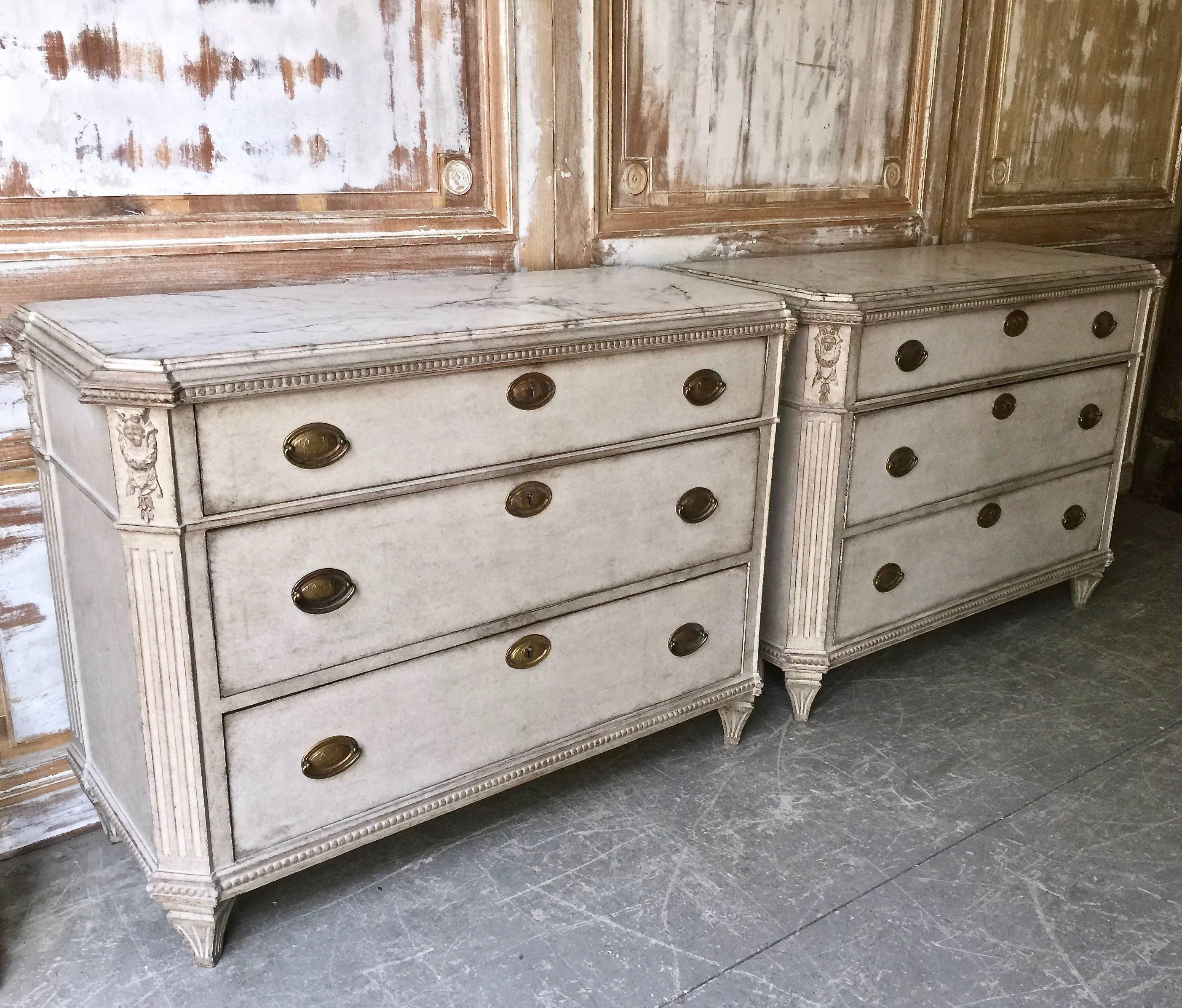 A very fine pair of 19th century, Swedish Gustavian Style chest of drawers with very handsome original hardware and exceptional figural carvings on each four reeded corner posts under the marblesized wood shaped top. A truly special pair of