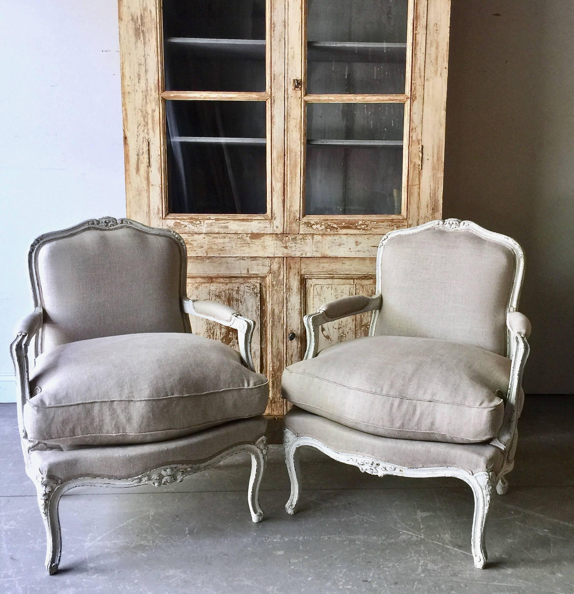 A pair of French painted fauteuils in Louis XV style with elegant carved floral details on shaped back rail, knees and aprons. Upholstered in neutral color linens with down/feather filled cussion and the classic gimp trim.
France, circa 1900.
Here