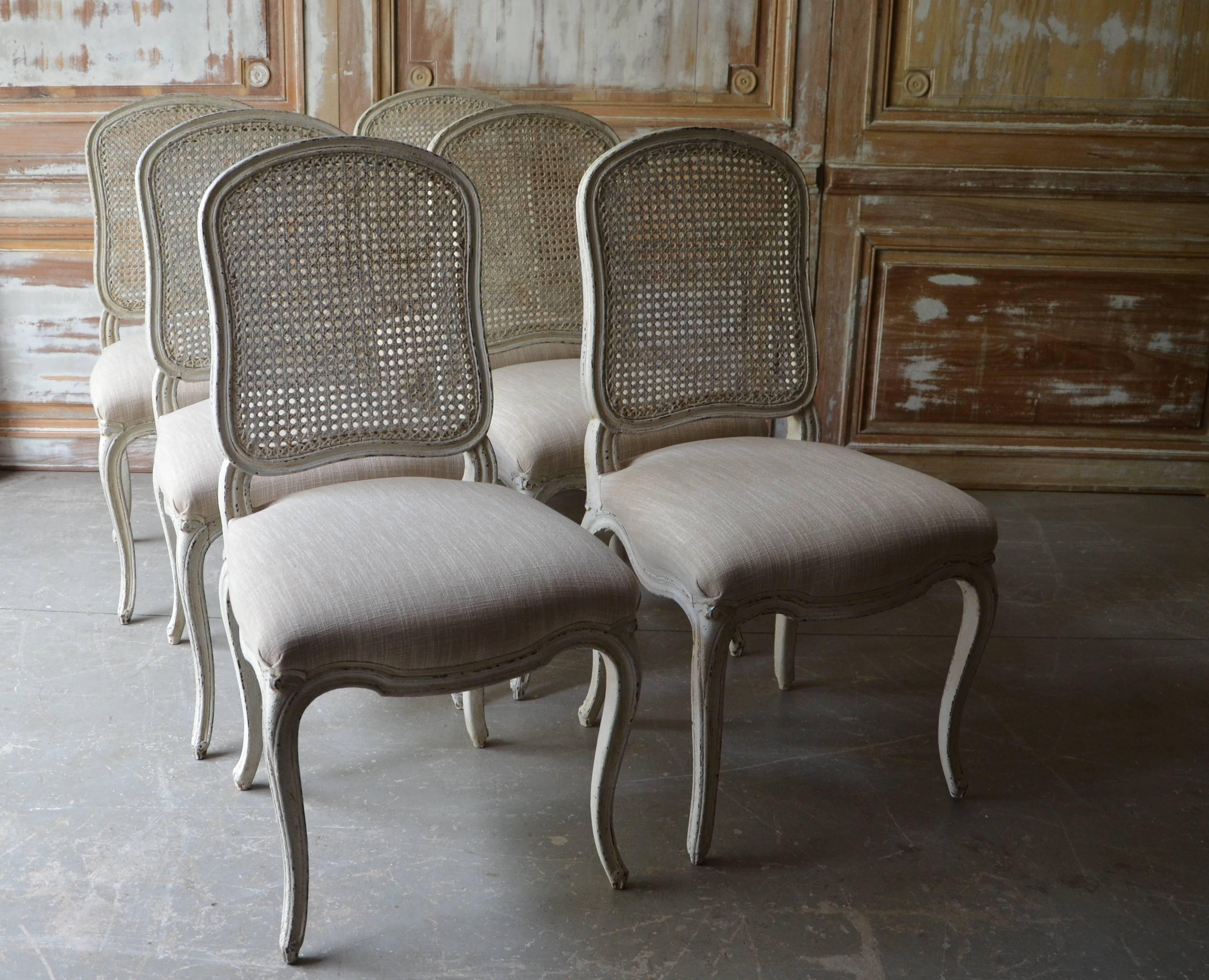 Set of French chairs Louis XV style with flat back called “la Reine” is caned and scalloped frieze carved and raised on cabriole legs. Upholstered in very light cream/white linen with classical decorative gimp trim. Very elegant as well as