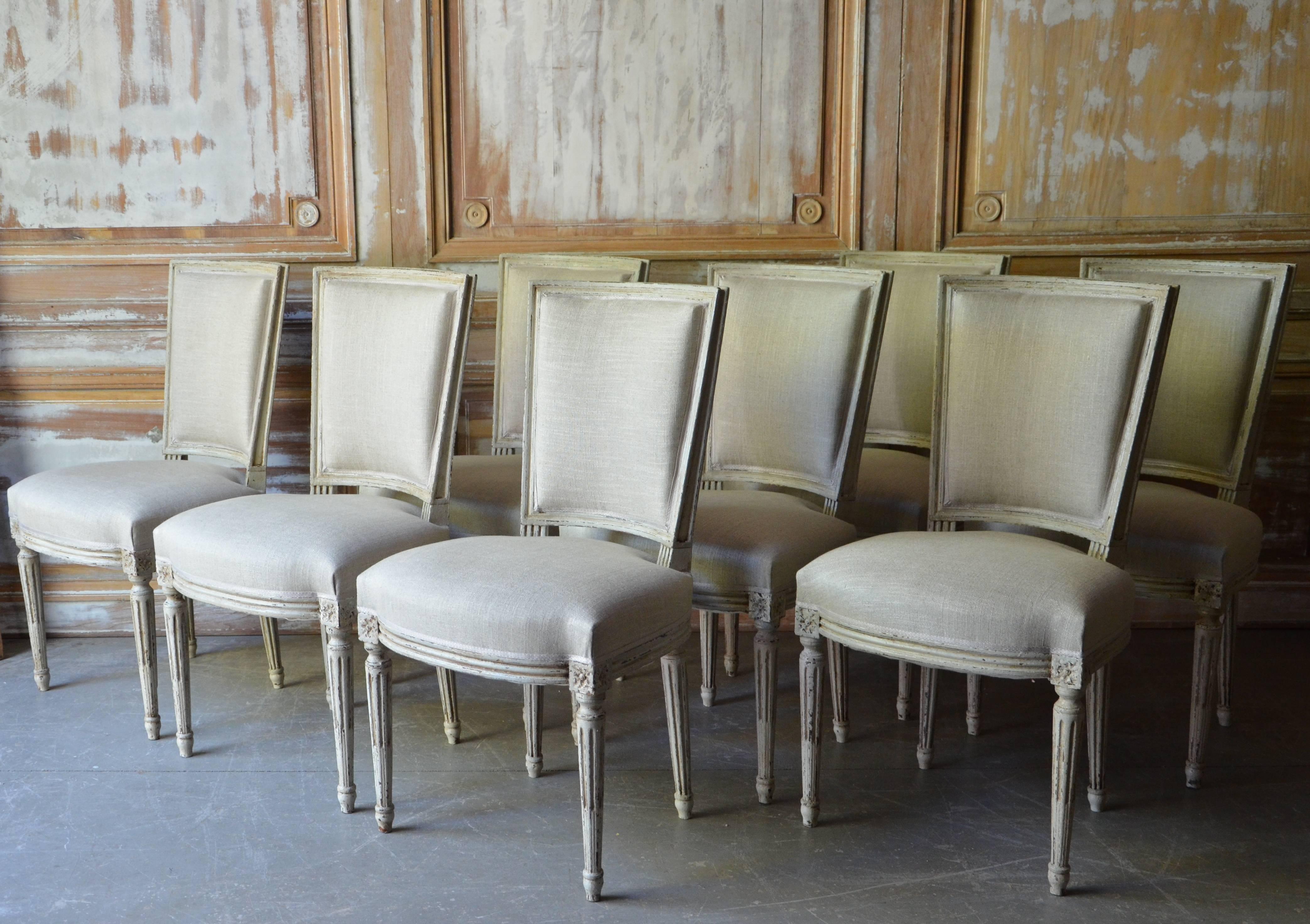 Set of eight, Louis XV style chairs with carved apron and corner blocks on turned tapering legs in worn white or cream patina. Upholstery in palest grey linen,
France, circa 1900

