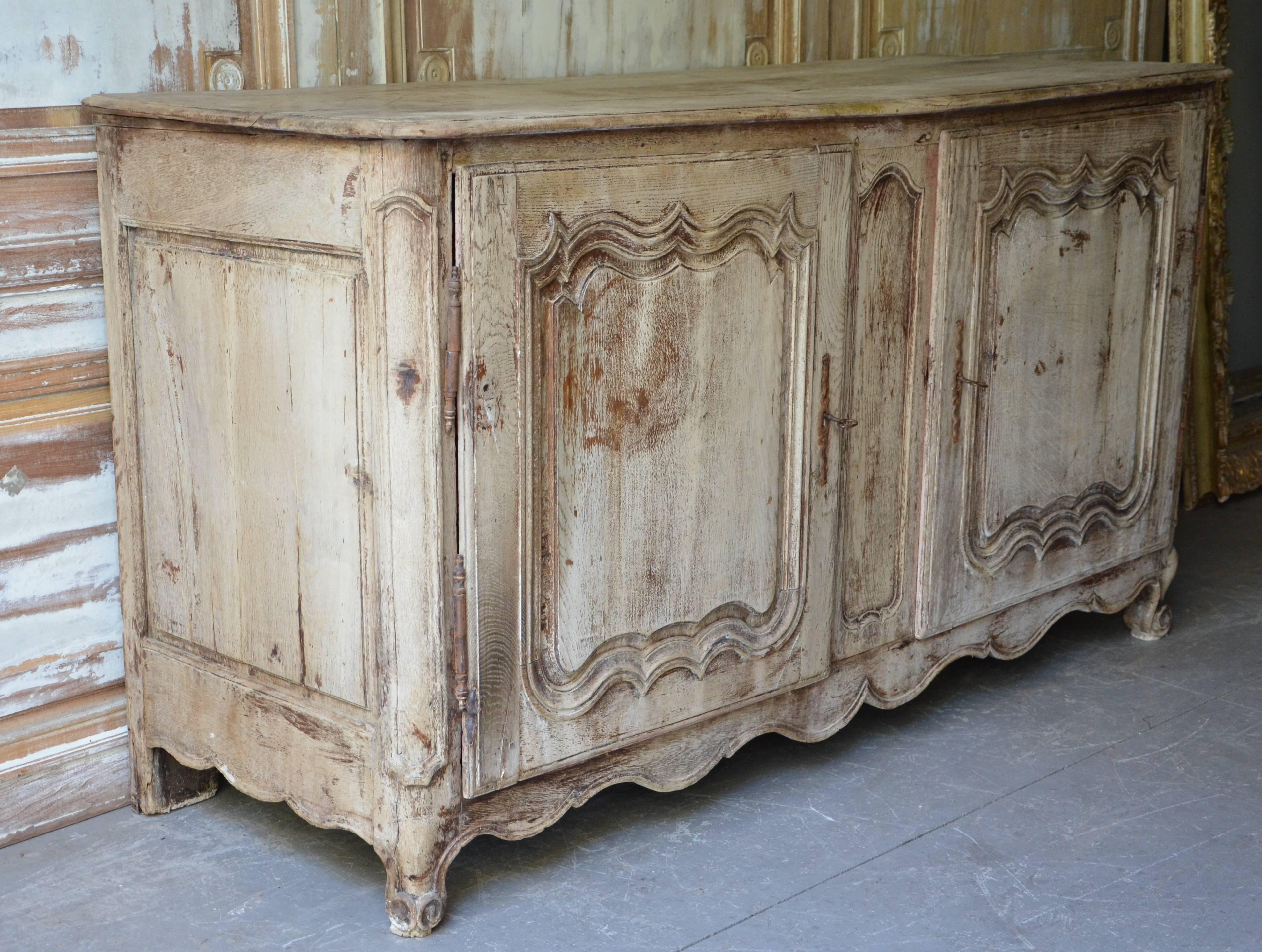 Early 19th century French Louis XV buffet with richly carved fielded door panels and beautiful shaped apron on short cabriole legs in superb patinated natural oak, France, circa 1840.