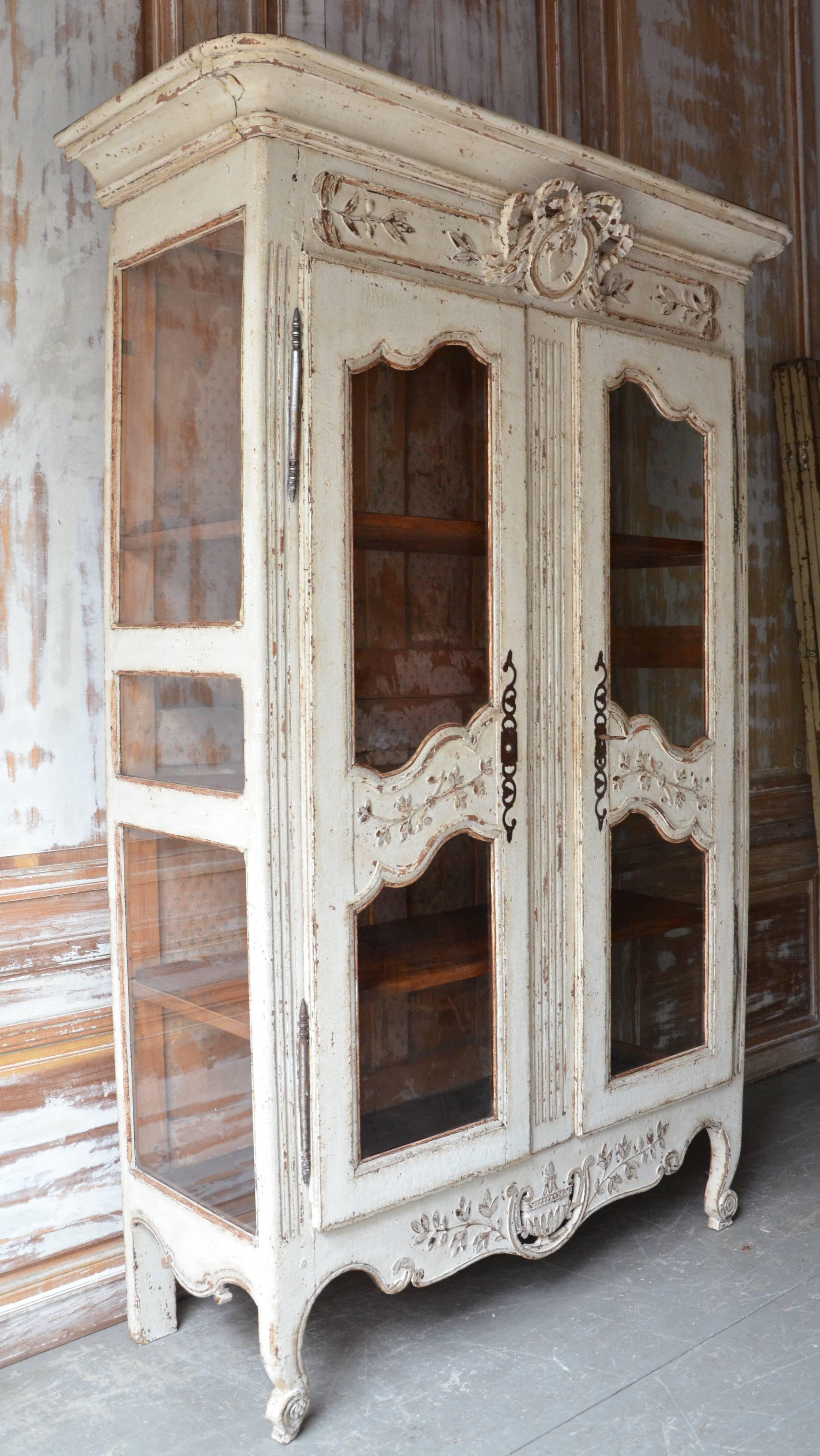 18th century French Louis XV-style Bibliothèque/Vitrine in painted walnut wood with double glass doors, glass side panels, carved heart in relief to symbolize love, richly carved apron, original hardwares and three inside shelves. Part of the