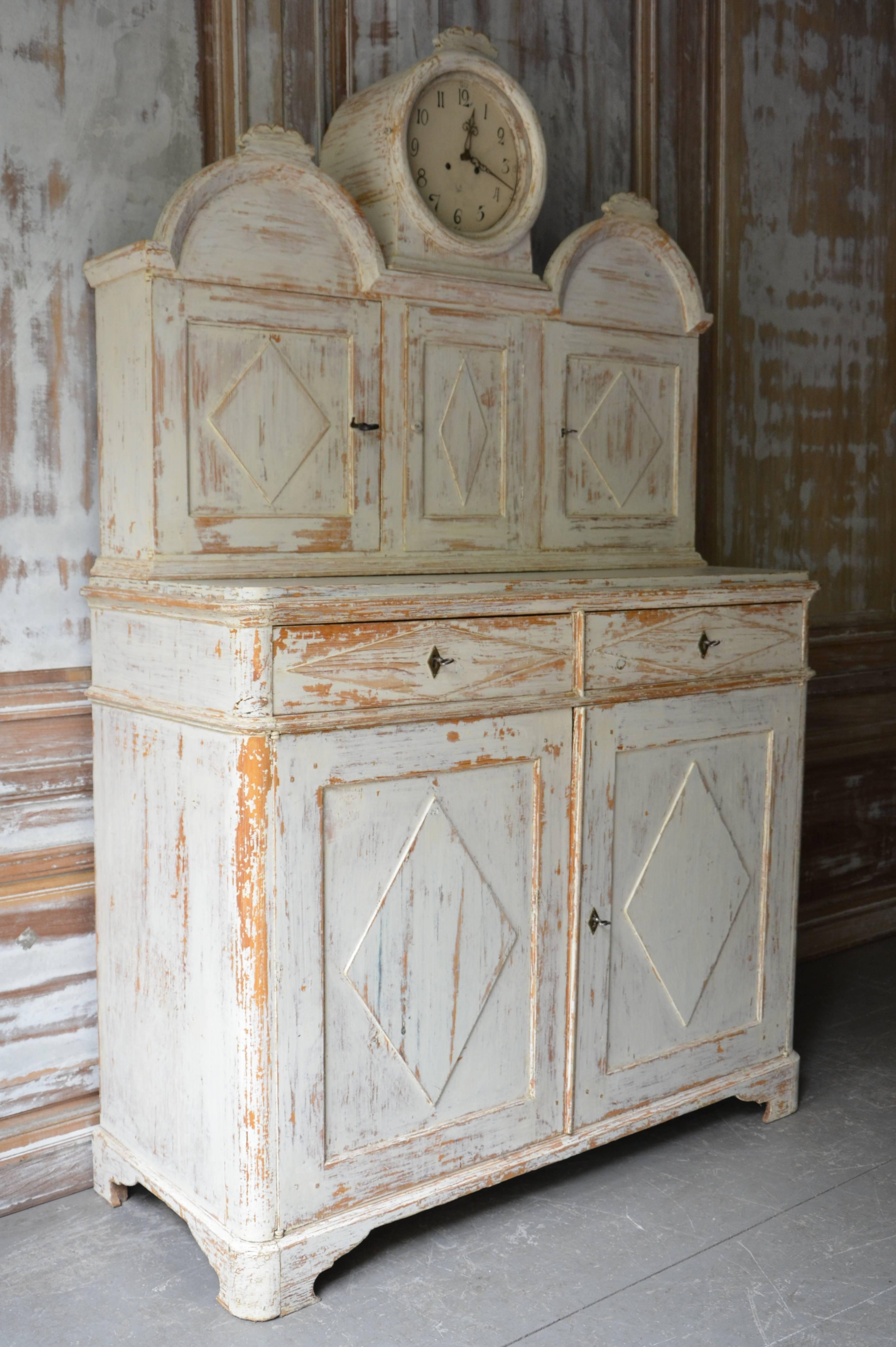Very rare Swedish Gustavian cupboard with clock.
Late Gustavian Swedish cabinet comes in two parts and displays Classic Gustavian styling including raised panel doors with diamond chapped decors on each side of the clock casing, original hardware.