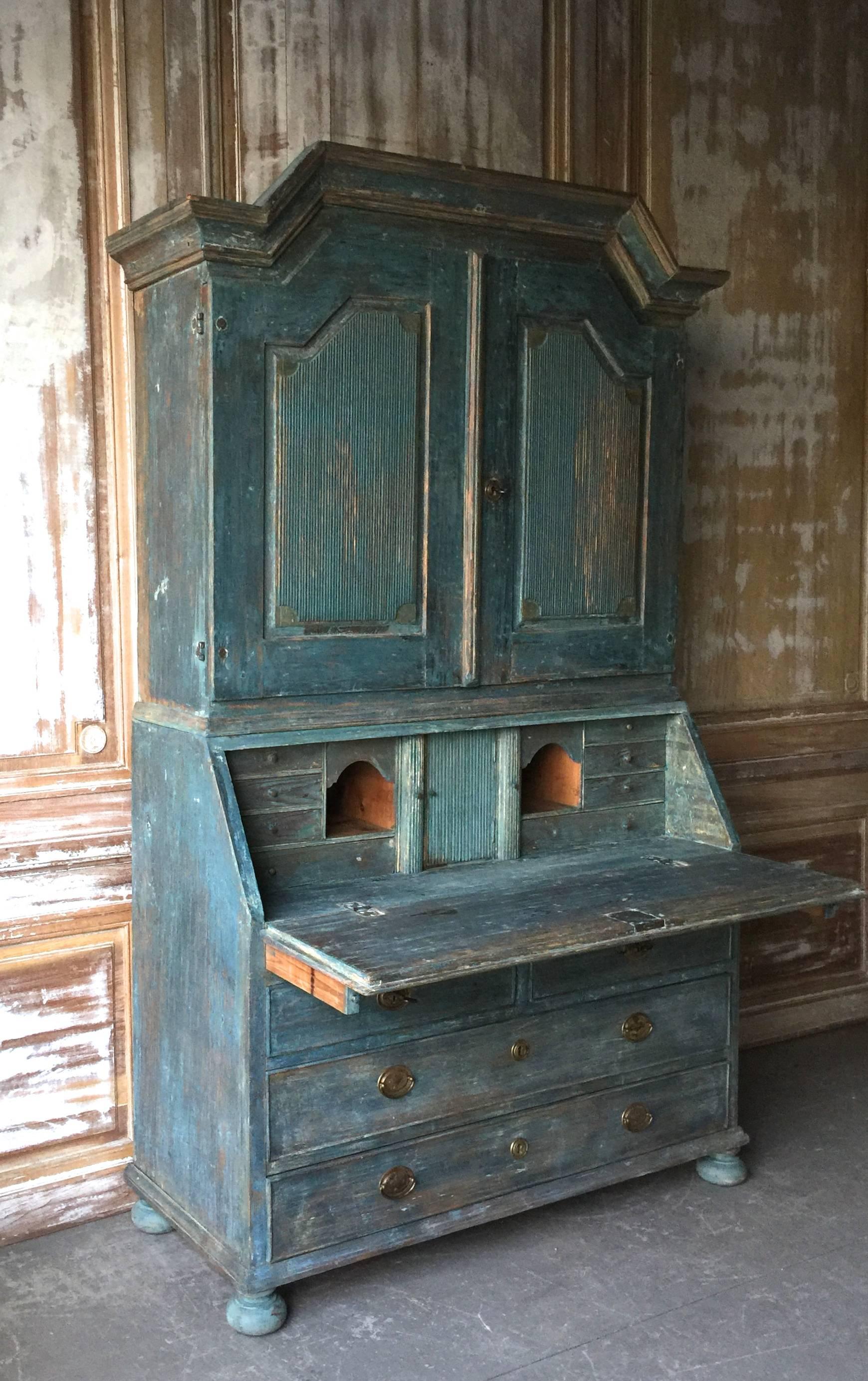 A very fine example of early 19th century secretaire cabinet of Gustavian period with a high arching pediment cornice and reeded panelled doors. The fall front desk with multitude of drawers and compartments in wonderful sky blue paint over the