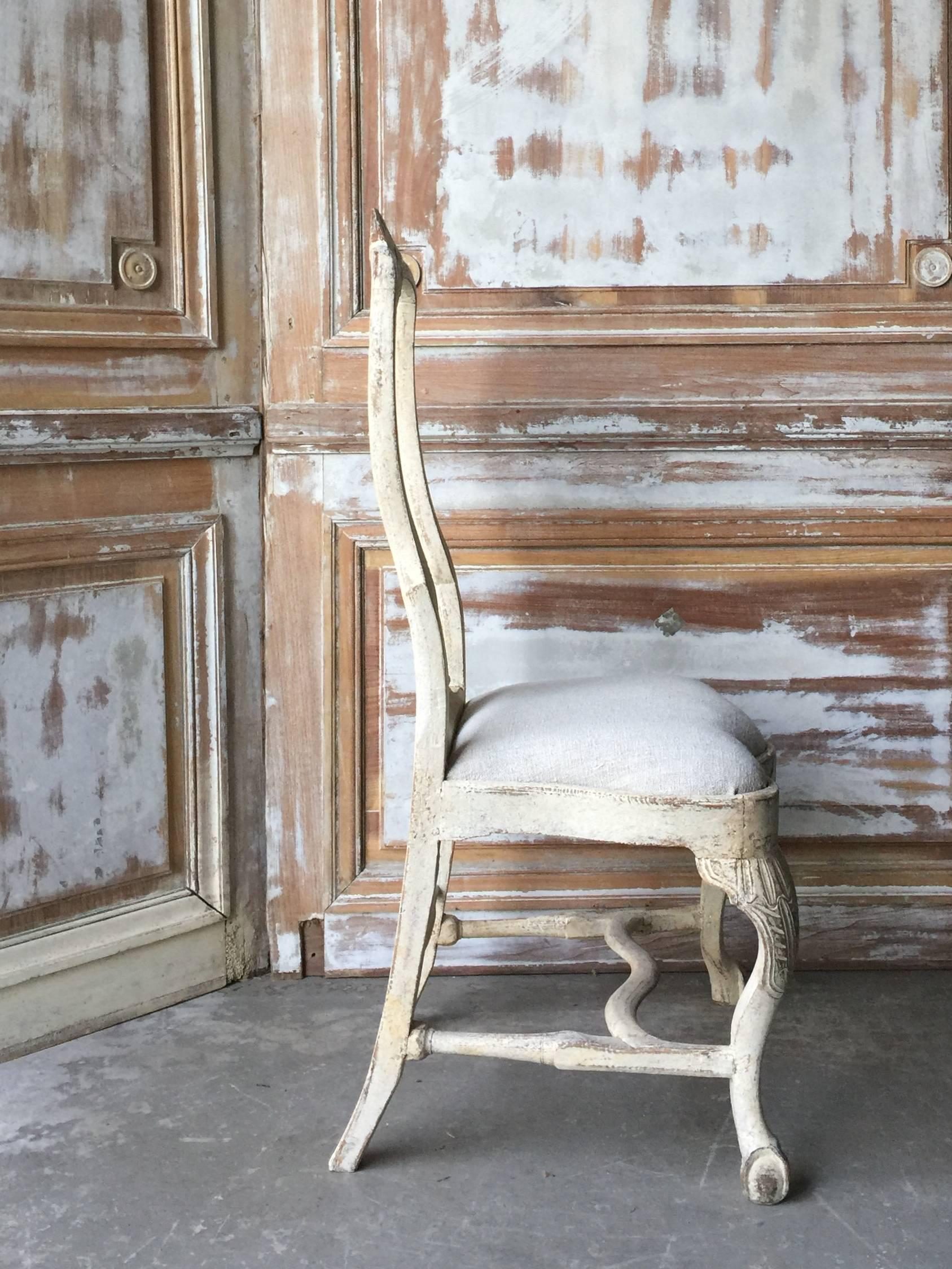 18th century Swedish chair, in Rococo period, circa 1760. Lovengly handmade with rocaille carving on the seat rails and pierced splats. Hand scraped back to traces of their original worn cream paint, Gothenburg, Sweden. Measures: Seat 14