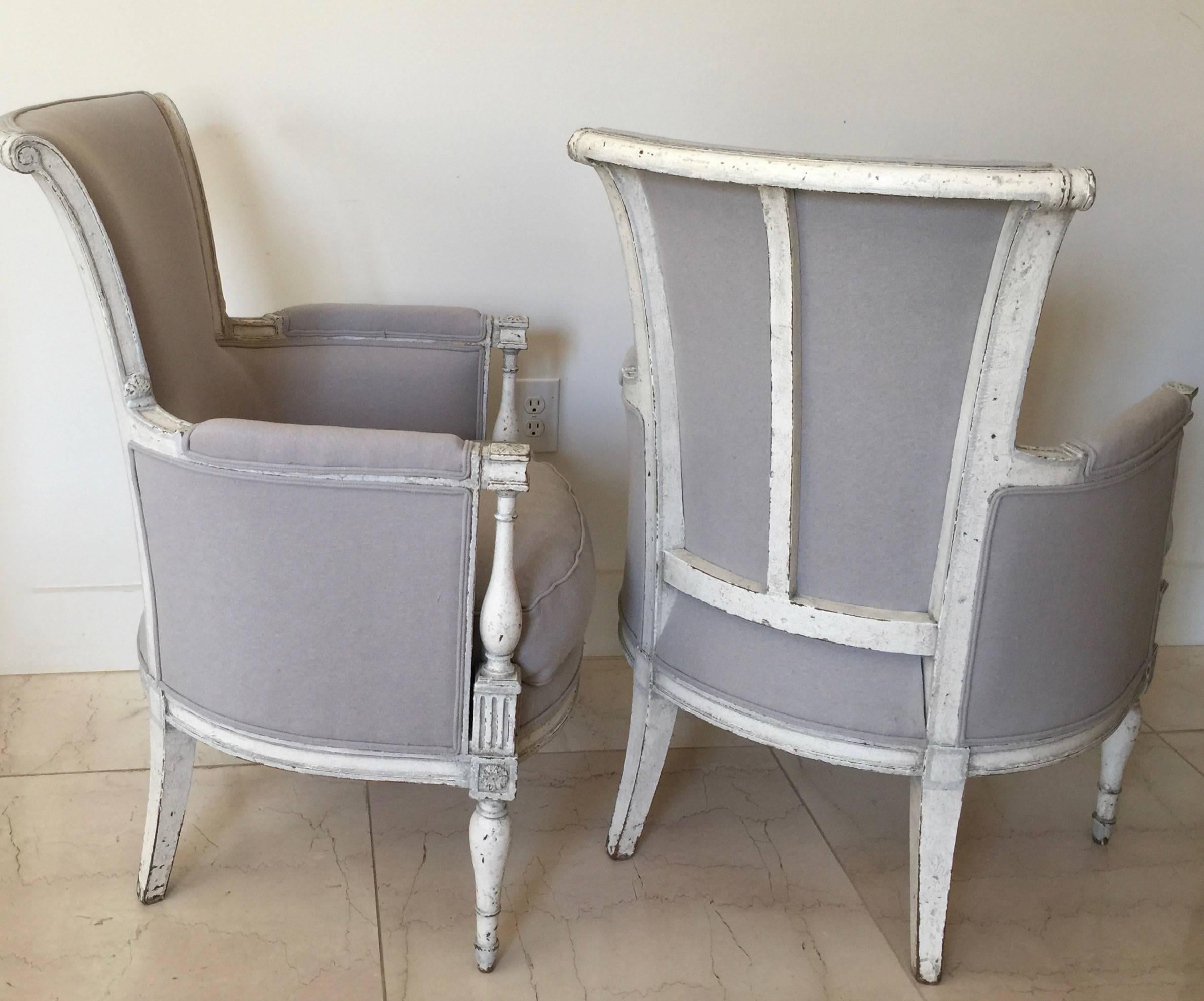 A pair of painted 19th century French Directoire style Bergères. The horned backs (à cornes) are coved with side and top rails that curve inward to create horns at the corners and terminating in scrolls, the armrests consoles baluster shaped, the