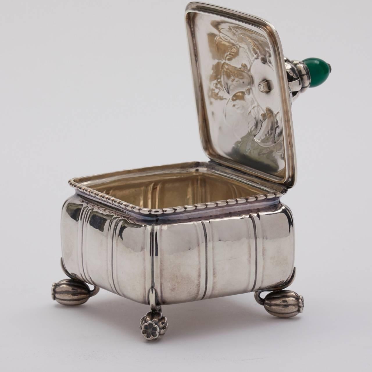 Georg Jensen sterling silver keepsake box, no. 30B.
Green agate finial.

Designed in 1913.
Exquisite hand-chased foliate details. Citron feet. Hinged lid.

Excellent patina, original condition. 
A similar example can be seen in the book