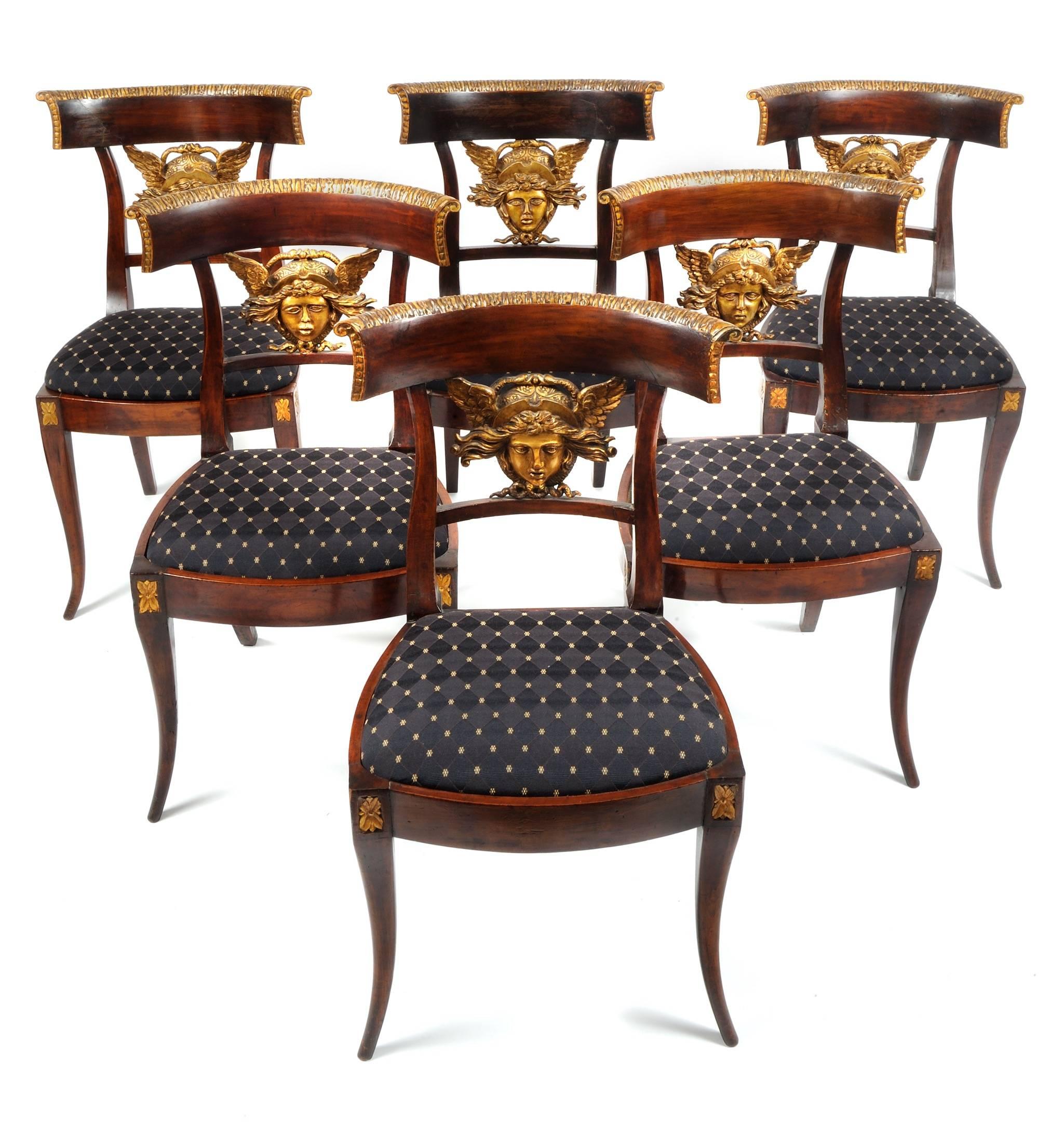 Set of six Italian (Lucca region) neoclassical carved klismos side chairs, circa 1810-1820. The splat of each chair features a stylized carved giltwood head of Medusa, each with slight variations of expression. 

The Medusa has been immortalized in