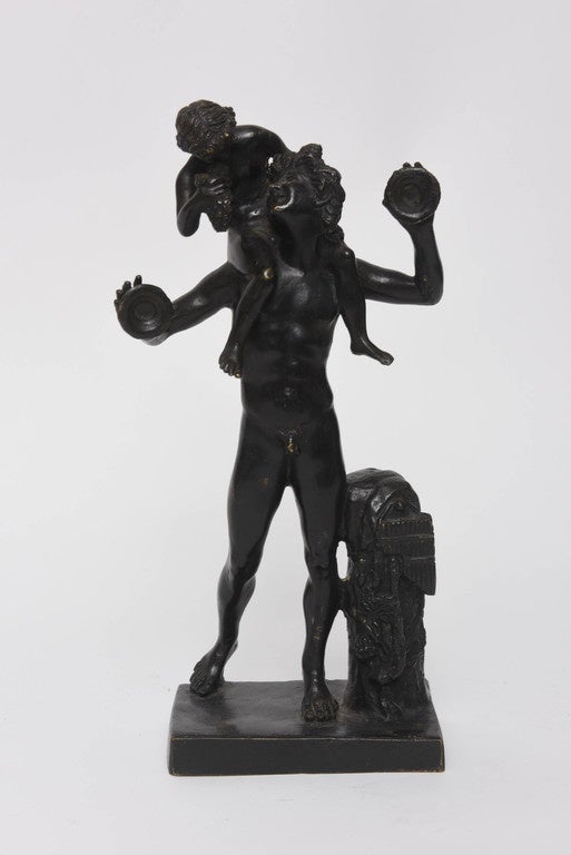 The sculpture depicts the faun with cymbals, leaning against a naturalistic stump, hung with a set of pan pipes and the infant Bacchus sitting on pan's shoulders holding a group of grapes.