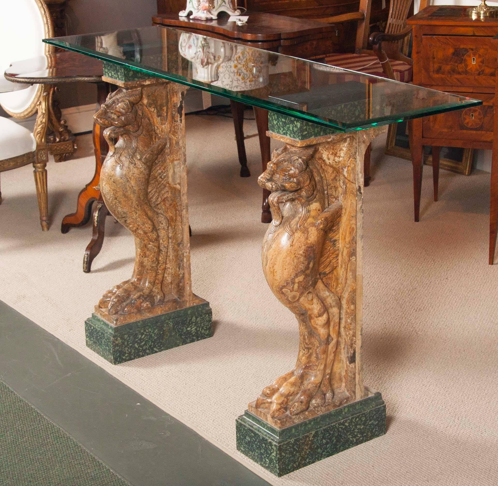 A late 18th century Italian neoclassical console table with two mythical "chimera" or lion's head, wings and feet-shaped pedestal or balustrade; mounted on a later marble base, back and top support. The tempered glass top is new.