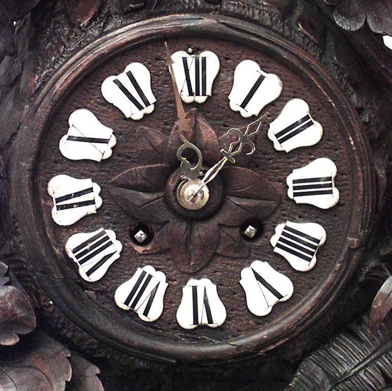 Horloge de cheminée rustique en noyer sculpté de la Forêt-Noire (19e siècle) avec un motif floral et une figure d'oiseau aux ailes déployées sur le dessus et 2 figures d'oiseaux en dessous. (Ne fonctionne pas)
