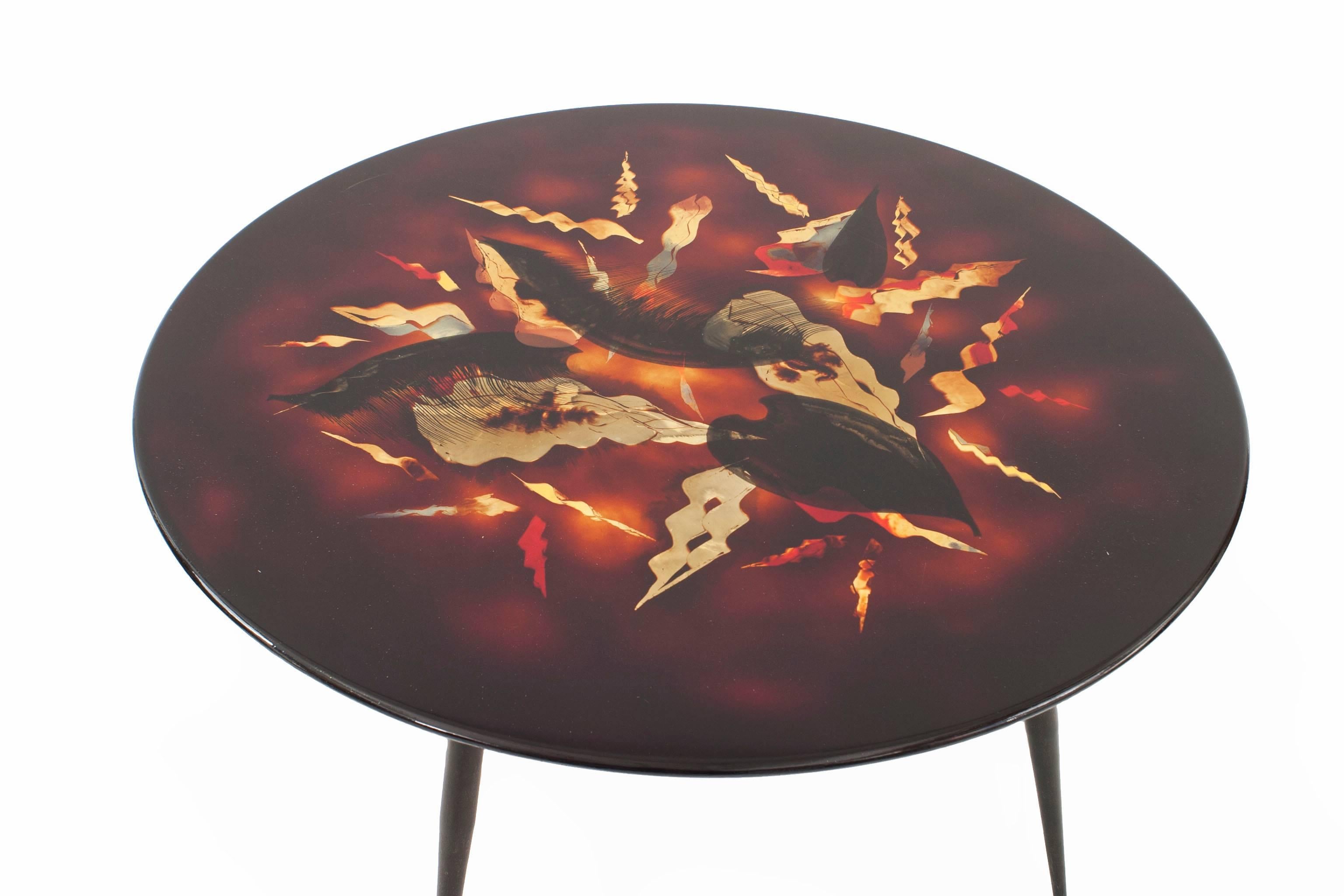 French midcentury low round top coffee table with a black and red geometric stylized leaf design top supported on 4 black metal legs with gilt bronze sabots (signed: BERNARD DUNAND).


Bernard Dunand was the son and close collaborator to Jean