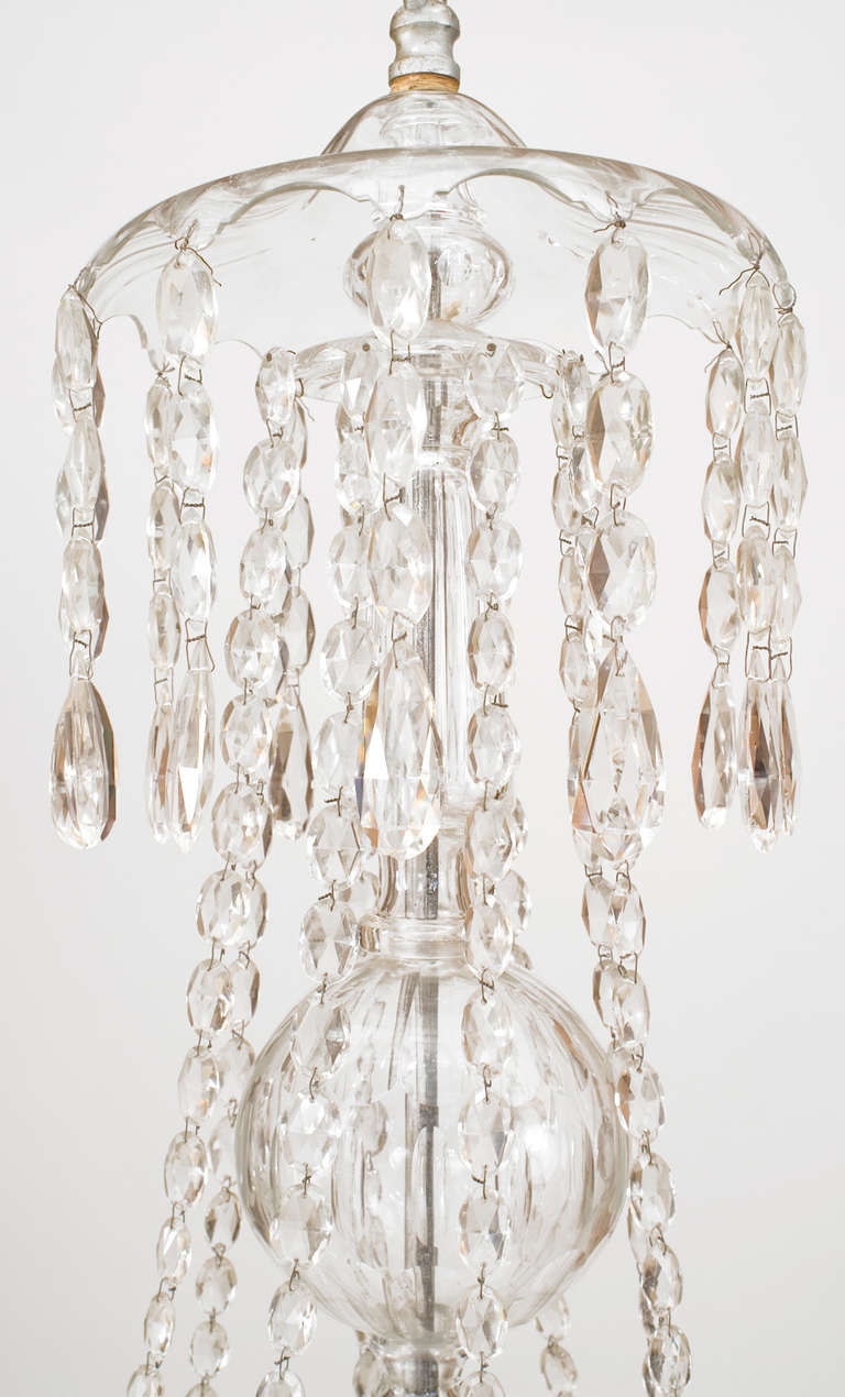 Continental Austrian (Possibly Mid-19th Century) crystal chandelier with 8 arms emanating from a crystal & scalloped silver gilt stem & draped with drops and pendants.
