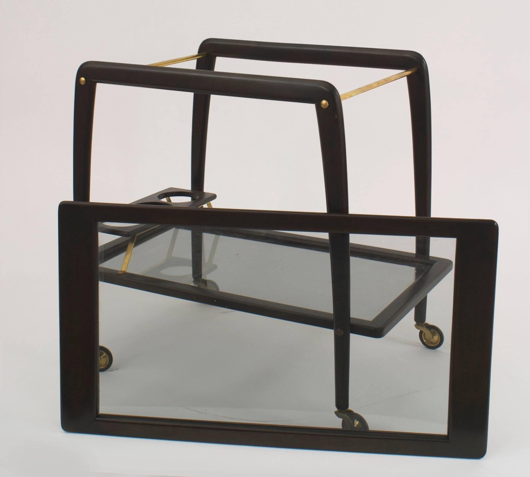 Italian Mid-Century (1950s) dark walnut liquor or drinks trolley bar cart on brass wheels having a removable glass tray top and bottom shelf with three bottle holders (by Ico Parisi, Cesare Lacca for Cassina).
