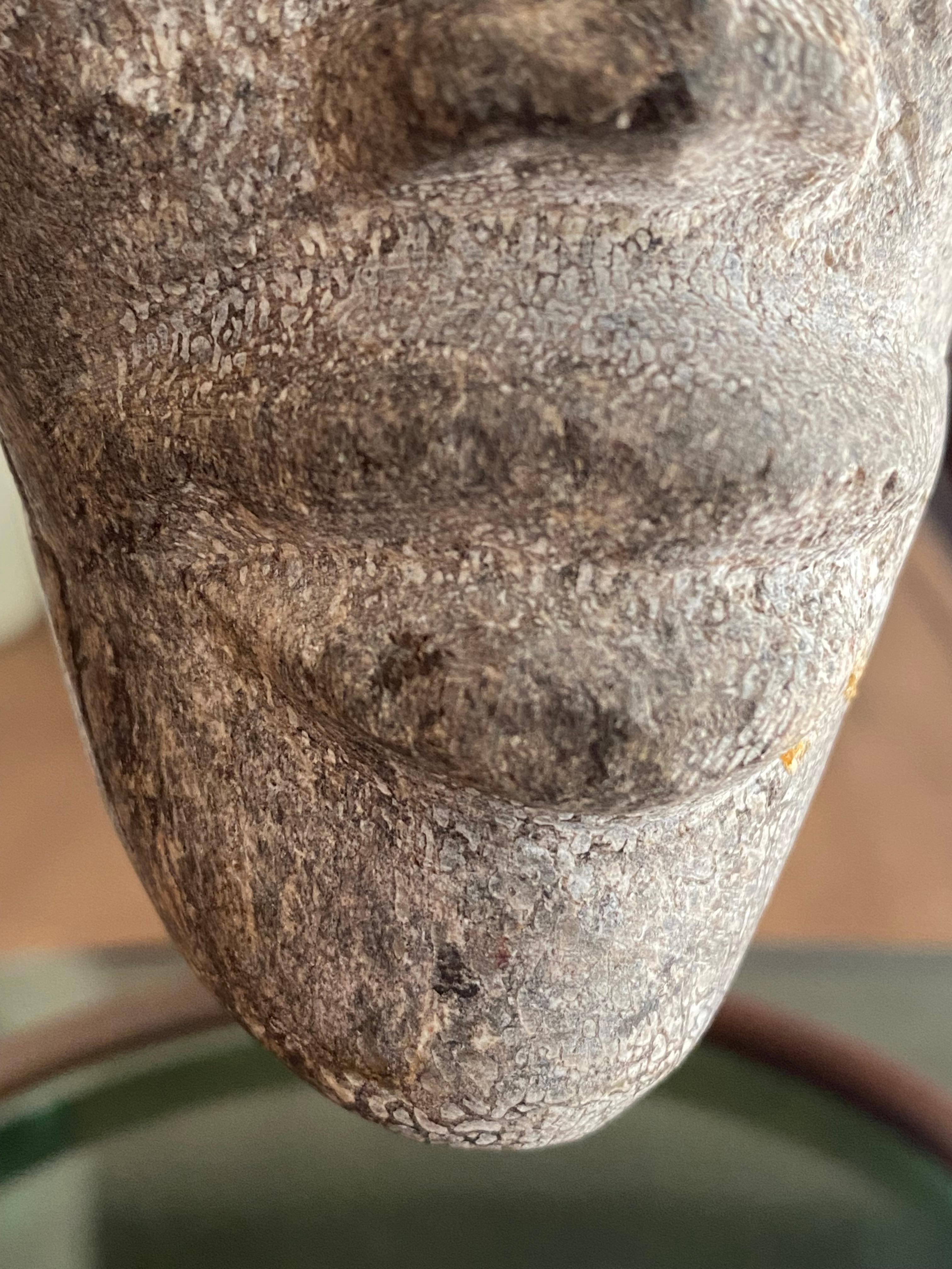Un visage en pierre sculptée très convaincant, monté sur un socle en acier soudé sur mesure. D'origine indonésienne, vers les années 1970, la sculpture présente des détails faciaux stylisés et une présence énigmatique. La surface présente les