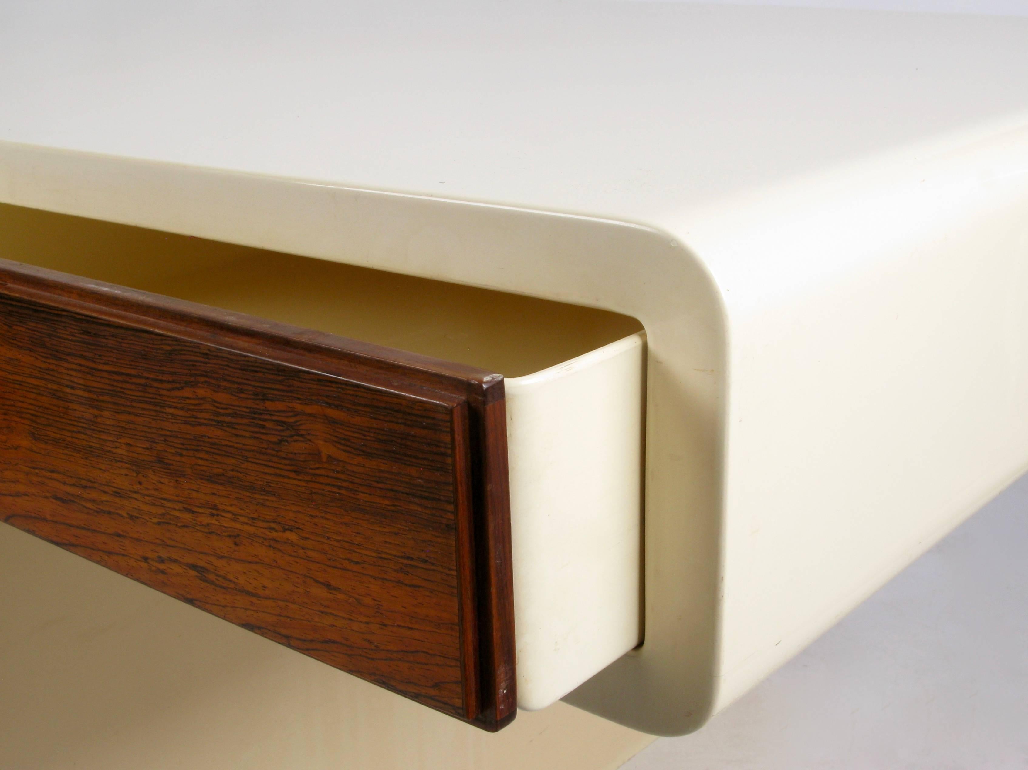 Large 1970s fiberglass coated cast resin desk designed by William Sklaroff for Vectra. The lacquered finish has aged beautifully from the original white to a warm ivory. Two rosewood fronted drawers on one side and a recessed rosewood panel across