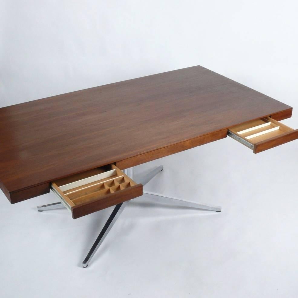 1960s walnut partner's desk designed by Florence Knoll. Features two drawers on each side of an expansive desk surface perched atop a chrome pedestal X-base. Retains original Knoll label.