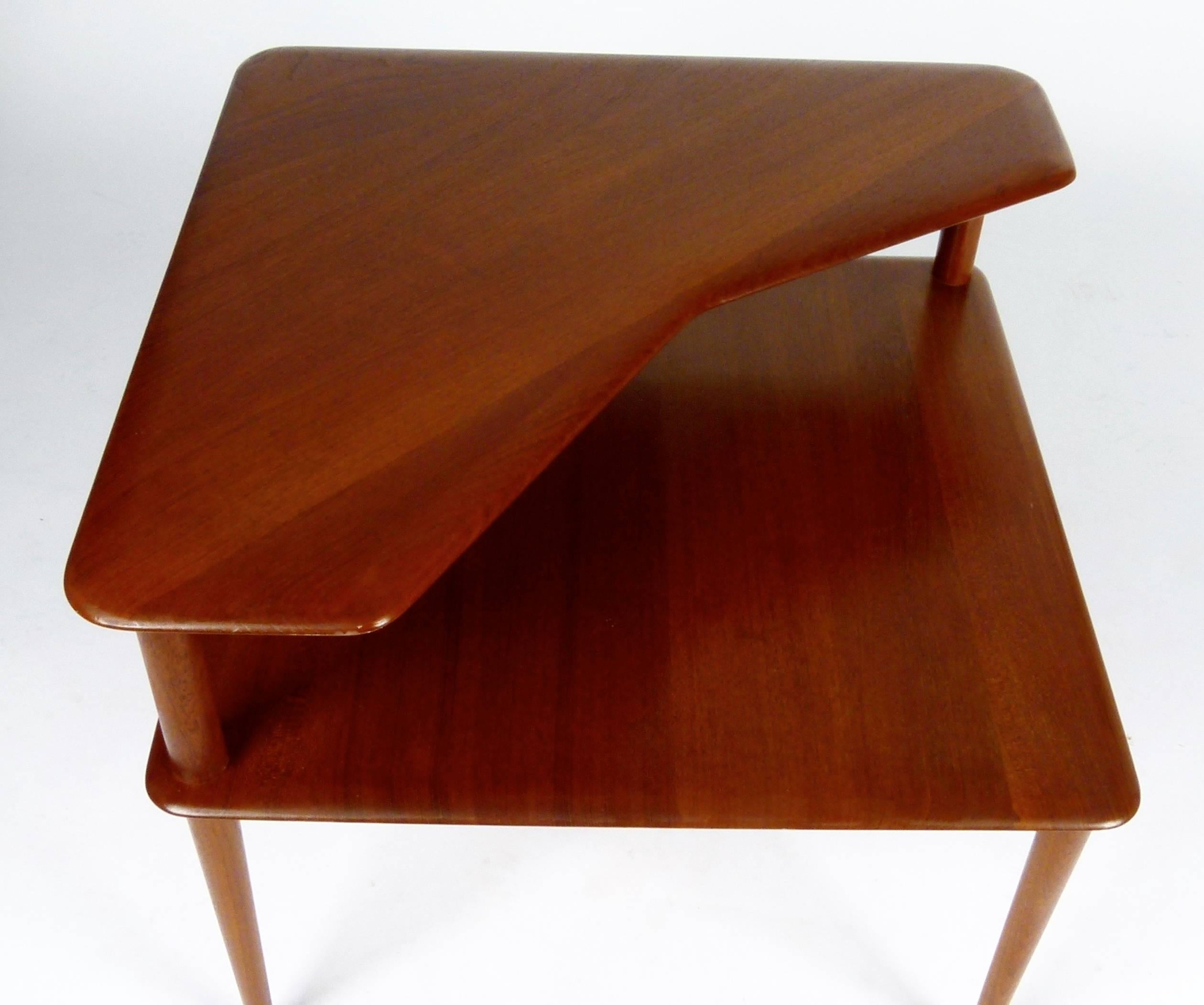 Beautiful, rare two-tier corner table in solid oiled teak designed by Peter Hvidt and Orla Molgaard-Nielsen for France & Son, Denmark, circa 1955. Excellent restored condition.