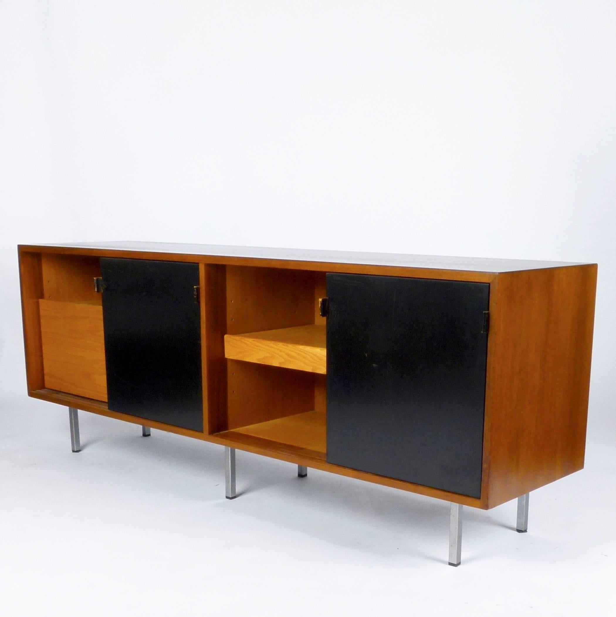 Walnut credenza with six black lacquered sliding doors, six steel legs, five drawers, three adjustable shelves, one pull-out shelf and leather door pulls by Florence Knoll, circa 1960. Retains Knoll label.