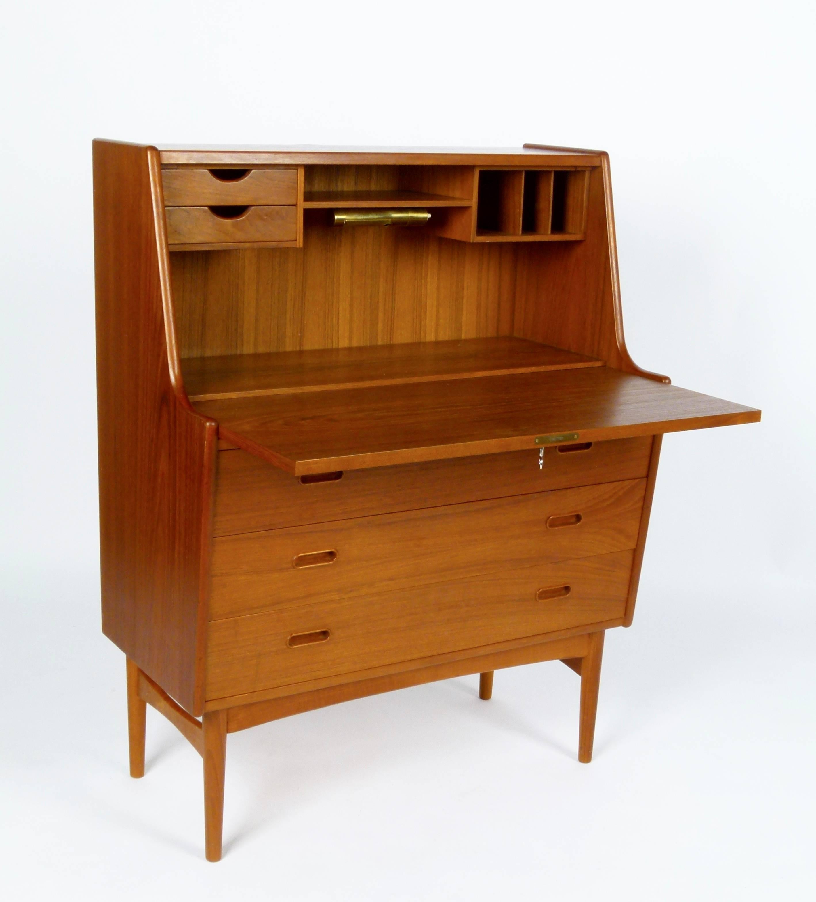 Very functional secretary in teak with three drawers and additional storage behind drop-front writing surface. Made by Vatne Mobler, Denmark. This beautifully maintained piece has its original oiled finish and key for locking the desk.