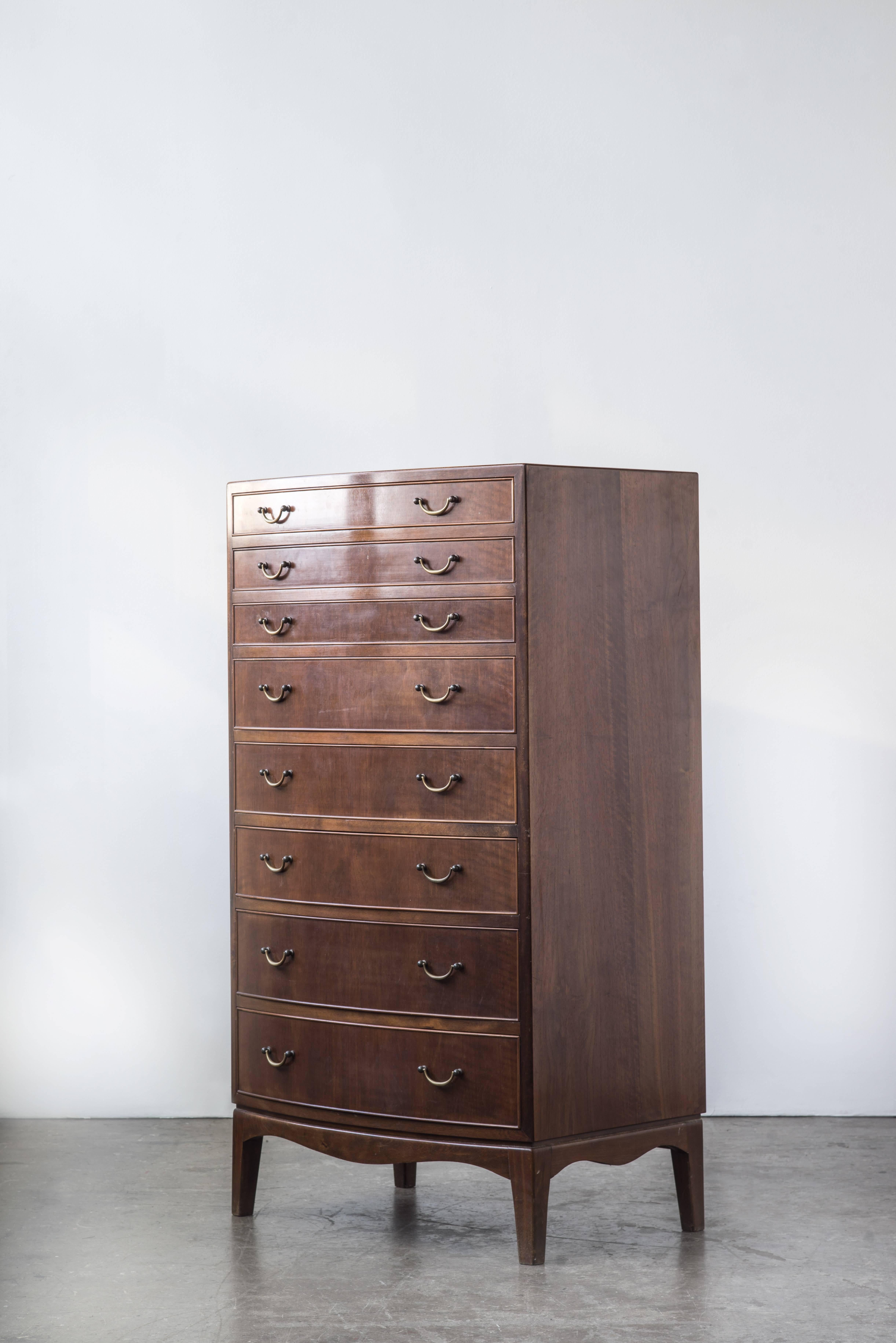A beautifully preserved tall dresser with a stained beach skeleton and facades of mahogany. Curved front with eight brass drawer pulls.
