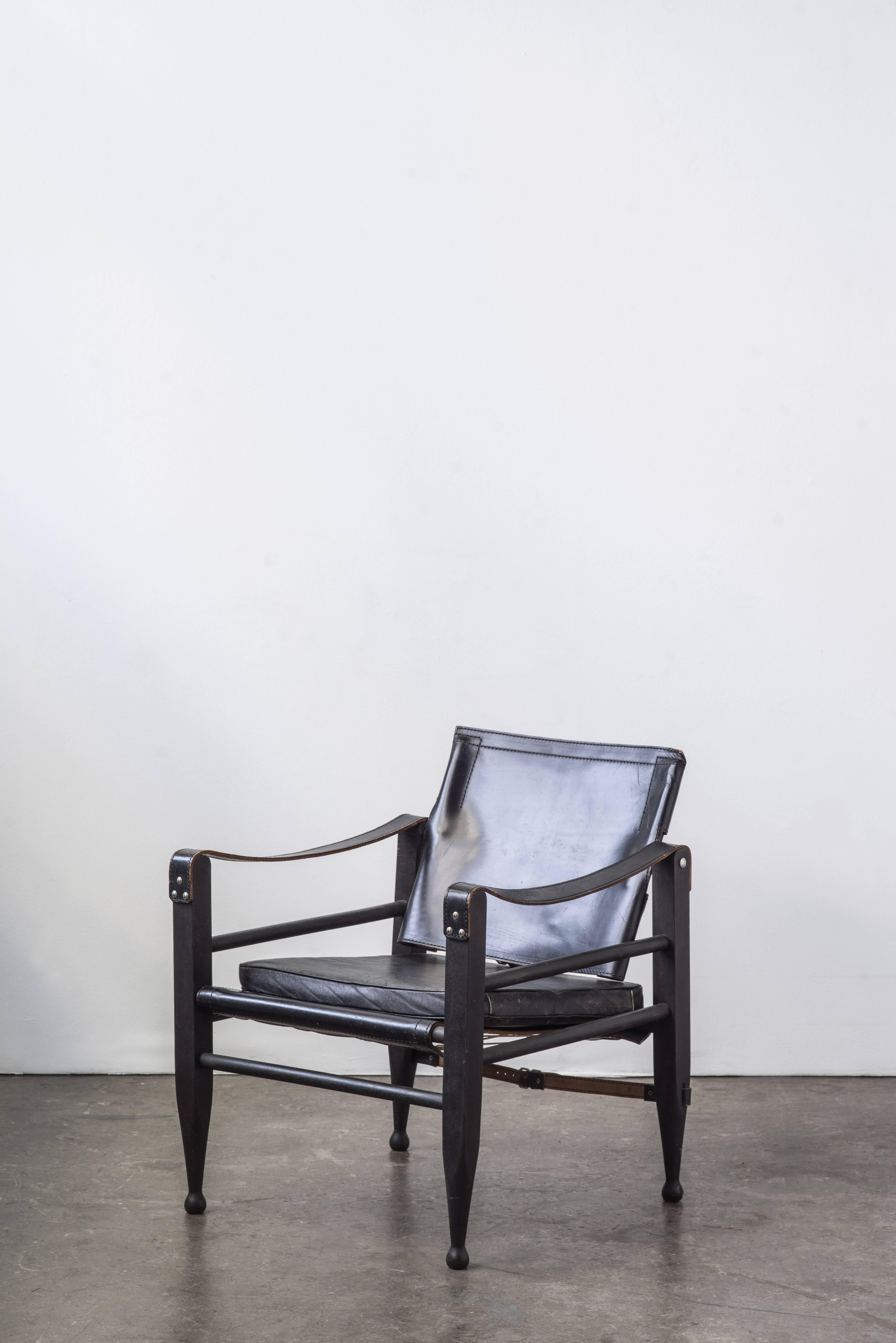 A pair of black leather safari Campaign chairs with painted wood frame. Extremely comfortable with a low stance and back. Many of these chairs have delicate cracking leather but this leather has been well maintained and still has considerable